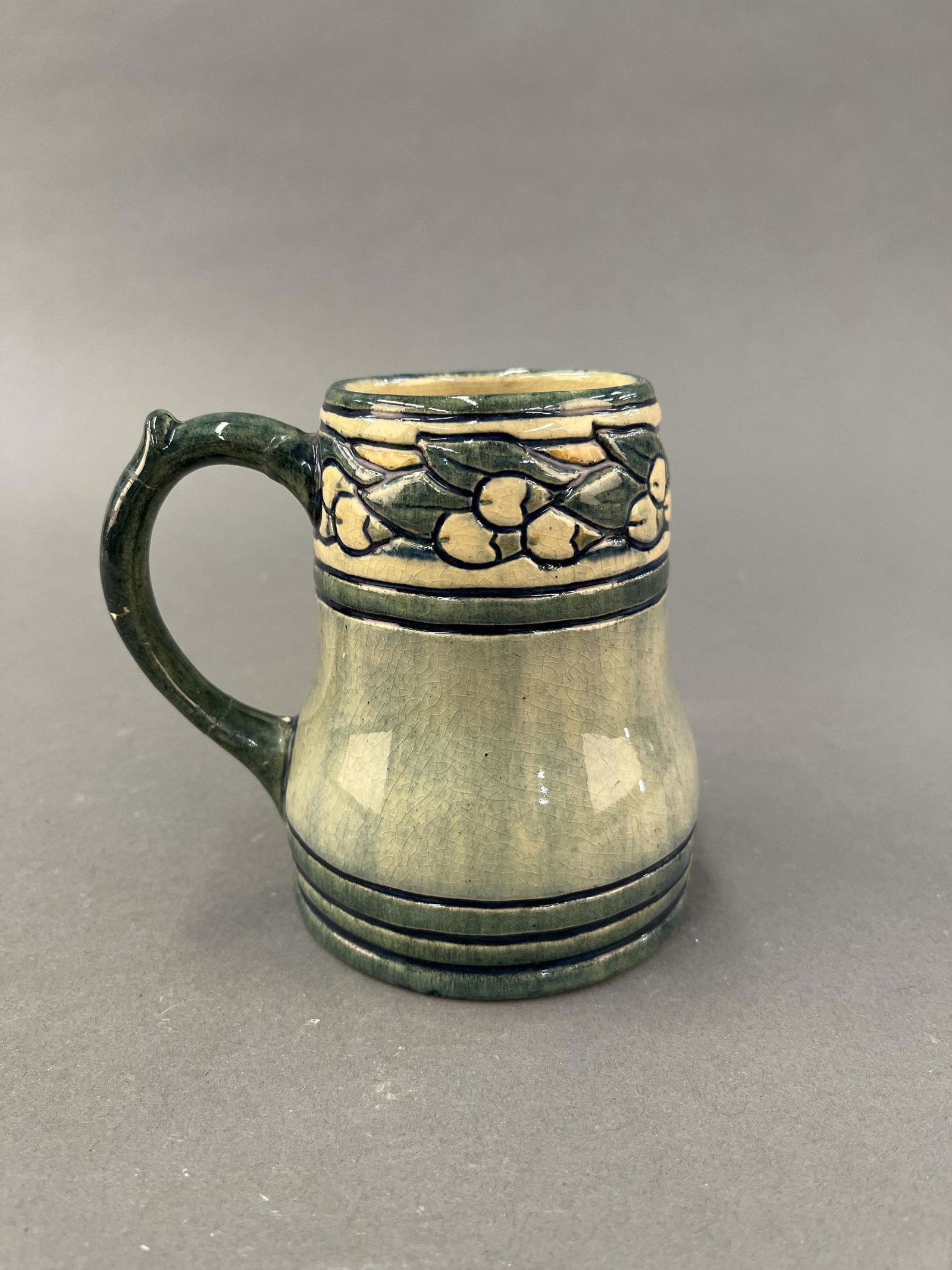 Marie De Hoa LeBlanc, Newcomb College mug.: A Marie De Hoa LeBlanc (1874-1954) for Newcomb College mug. New Orleans, LA. 1906. Green glaze with floral design around the rim. Stamped on base. BE58. 4 1/2" x 4 3/4".Provenance: From Sylvia and Dr.