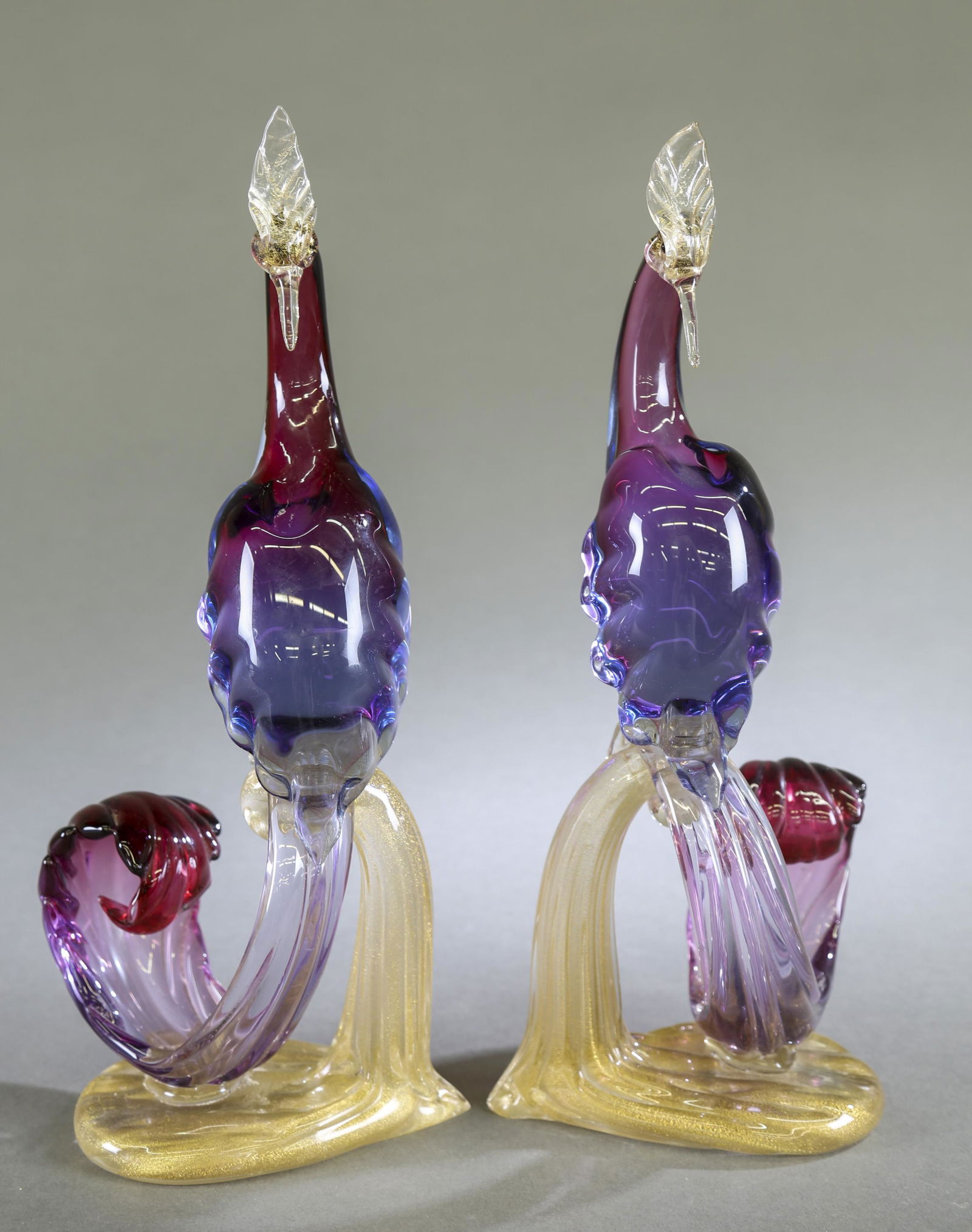 Pair of Alfredo Barbini Murano glass birds.: A pair of Murano glass peacocks by Alfredo Barbini (Italian, 1912-2007). Purple and dark pink toned birds on a gold speckled base. Unsigned.16 1/2" x 7".Provenance: From The Estate of Marvin Oleshansk
