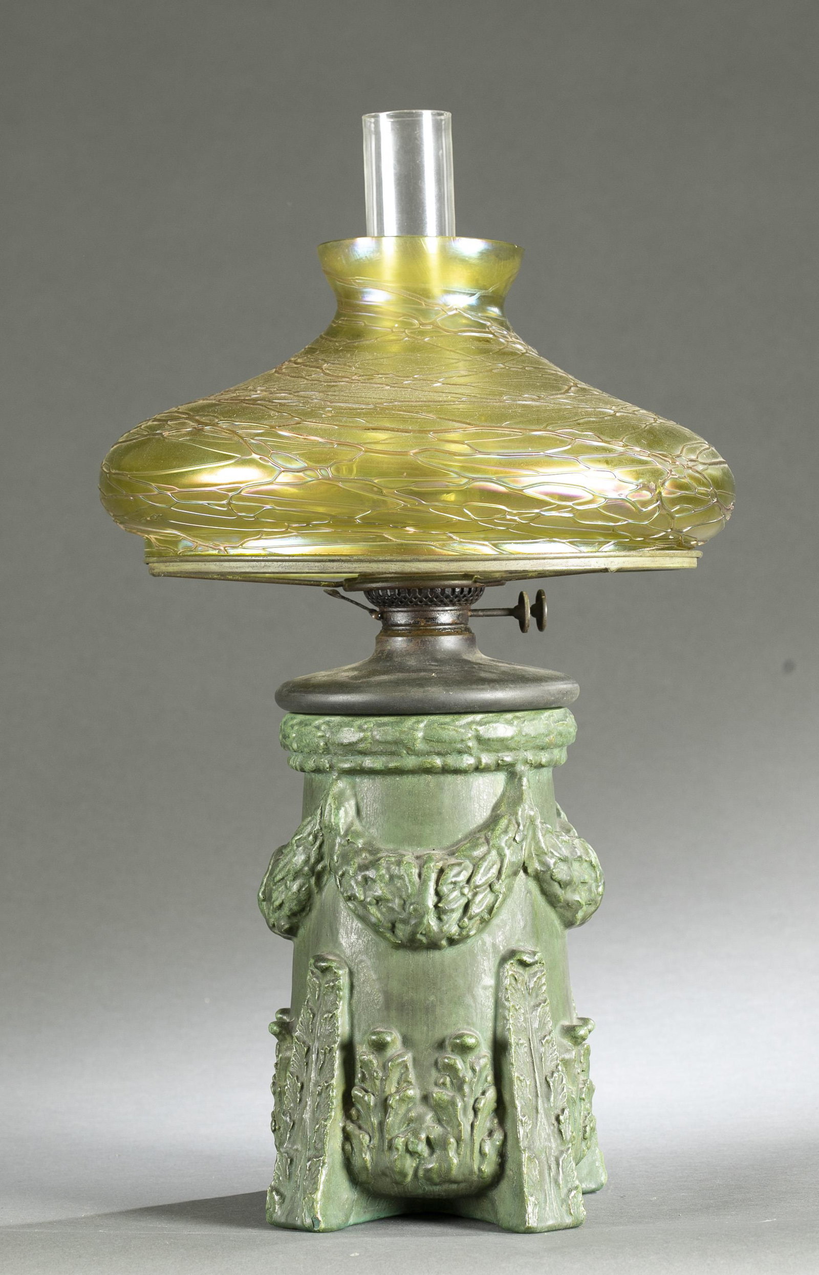 American Art Pottery oil lamp with glass shade.: An American Art Pottery kerosene oil lamp with Austrian glass shade. ++ Ceramic green glaze footed base with laurel swag and foliate design. Base unmarked. Base: 11 x 8 1/2". With kerosene insert: 16"