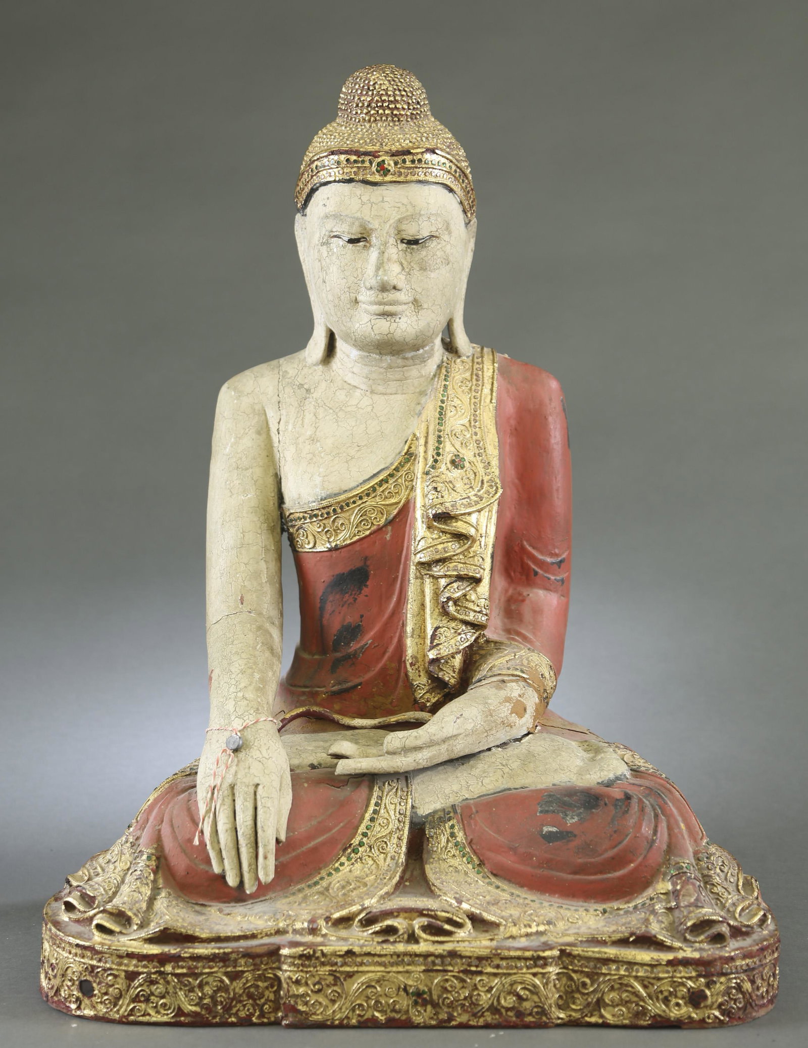 South East Asian wood Buddhist statue.: A South East Asian wood Buddhist statue. Sitting on the lotus pod. Kasaya in red lacquer, gilt in ribbon. 26" x 19".Condition: Lacquer peeling to the shoulder, legs and back. Cracks throughout due to 