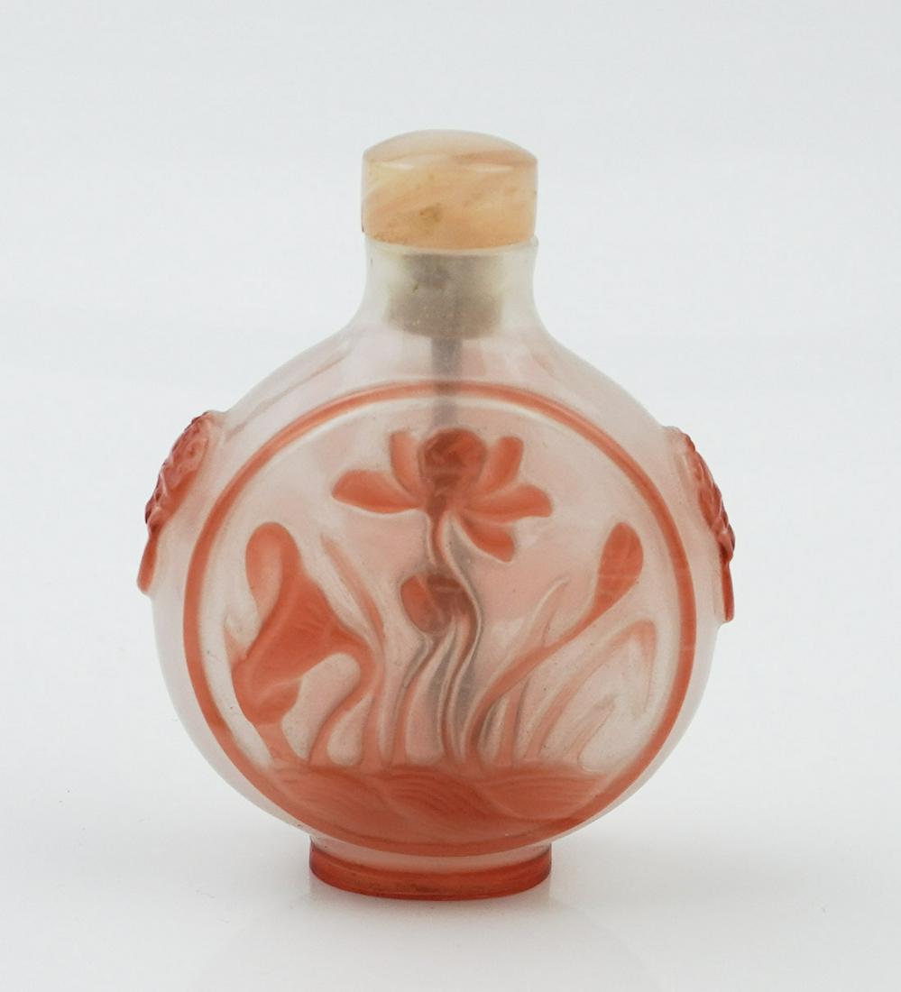 2 Chinese Peking glass snuff bottles.: A group of two Chinese Peking glass snuff bottles. Including one red Peking glass snuff bottle. Circa early Qing. In baluster body inlaid red glass featuring lotus and leaf. Foo dog hangers on both si