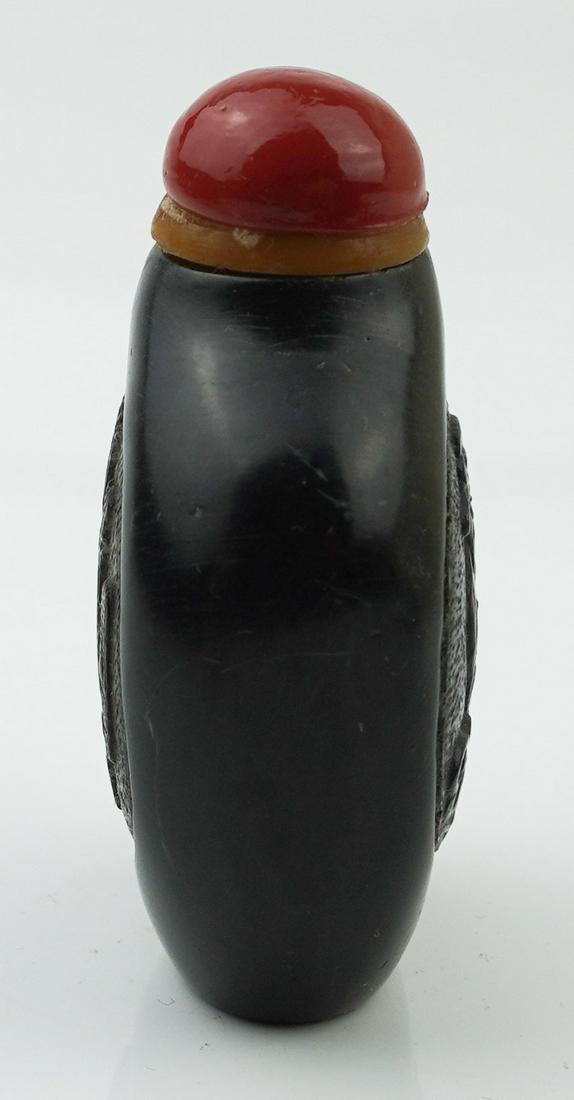 Chinese black soapstone snuff bottle.: A Chinese black soapstone snuff bottle, carved Qianlong mark to the bottom. In baluster form, carving a scholar to one side, and inscription to the other side. 2 3/4" x 1 7/8".Condition: One crack to