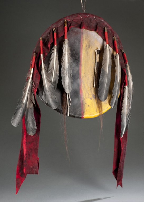 Animal hide shield.: Probably a modern reproduction. Decorated with feathers, red cloth and horse hair. 17 1/2h. x 17"w.