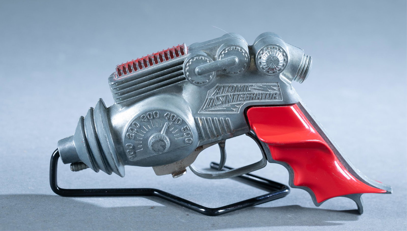 Hubley Atomic Disintegrator cap gun: A Hubley Atomic Disintegrator cap gun, Circa 1954. Die cast. 7 1/2" long.Condition: Loose and warped grips. Tarnish and rust on cap mechanism. Chipped red paint on top. Hammer fires.