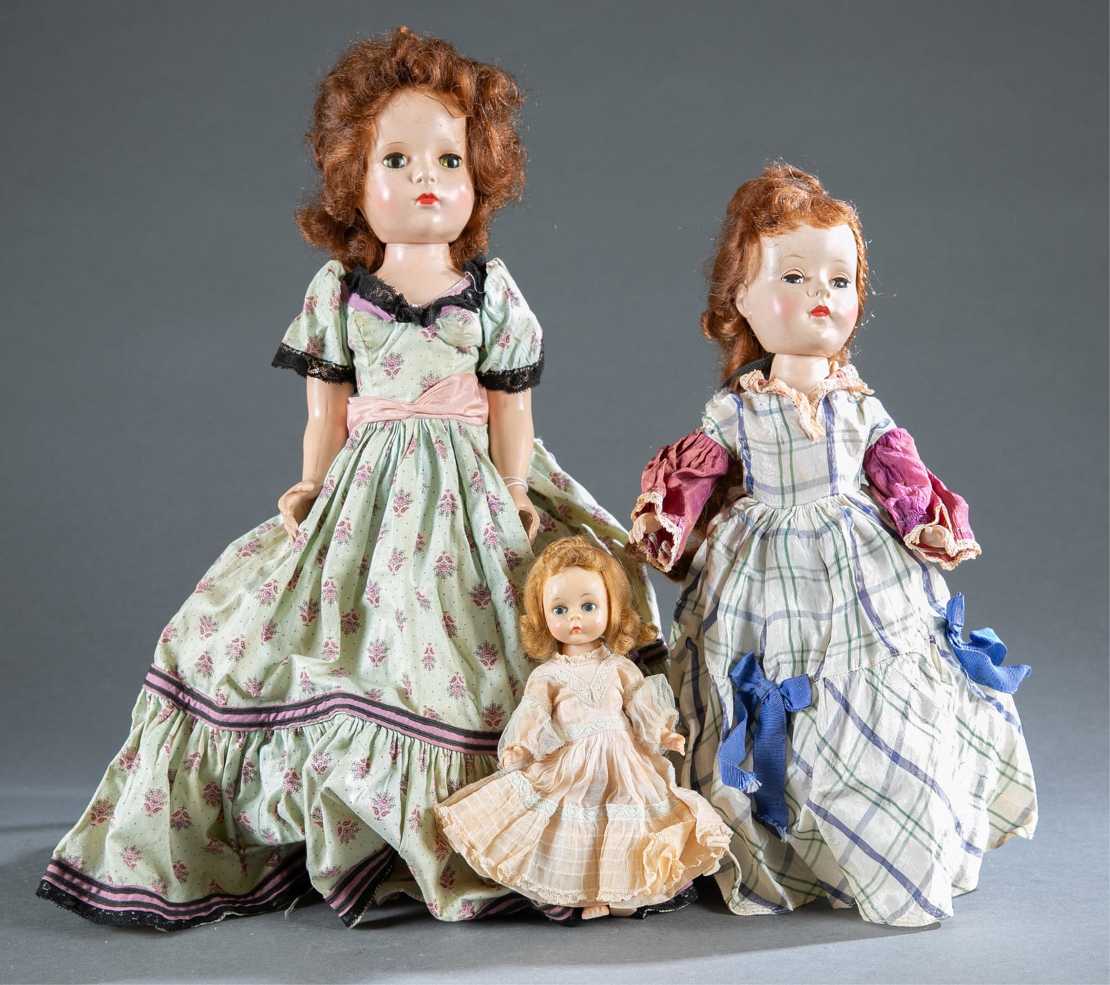 3 Madame Alexander hard plastic dolls .: A group of three Madame Alexander hard plastic dolls. ++ Glamour Girl Picnic Day doll, Circa 1953. Ruby lips, sleepy eyes. Cotton blue floral print gown with black lace trim, petticoat with hoop, and