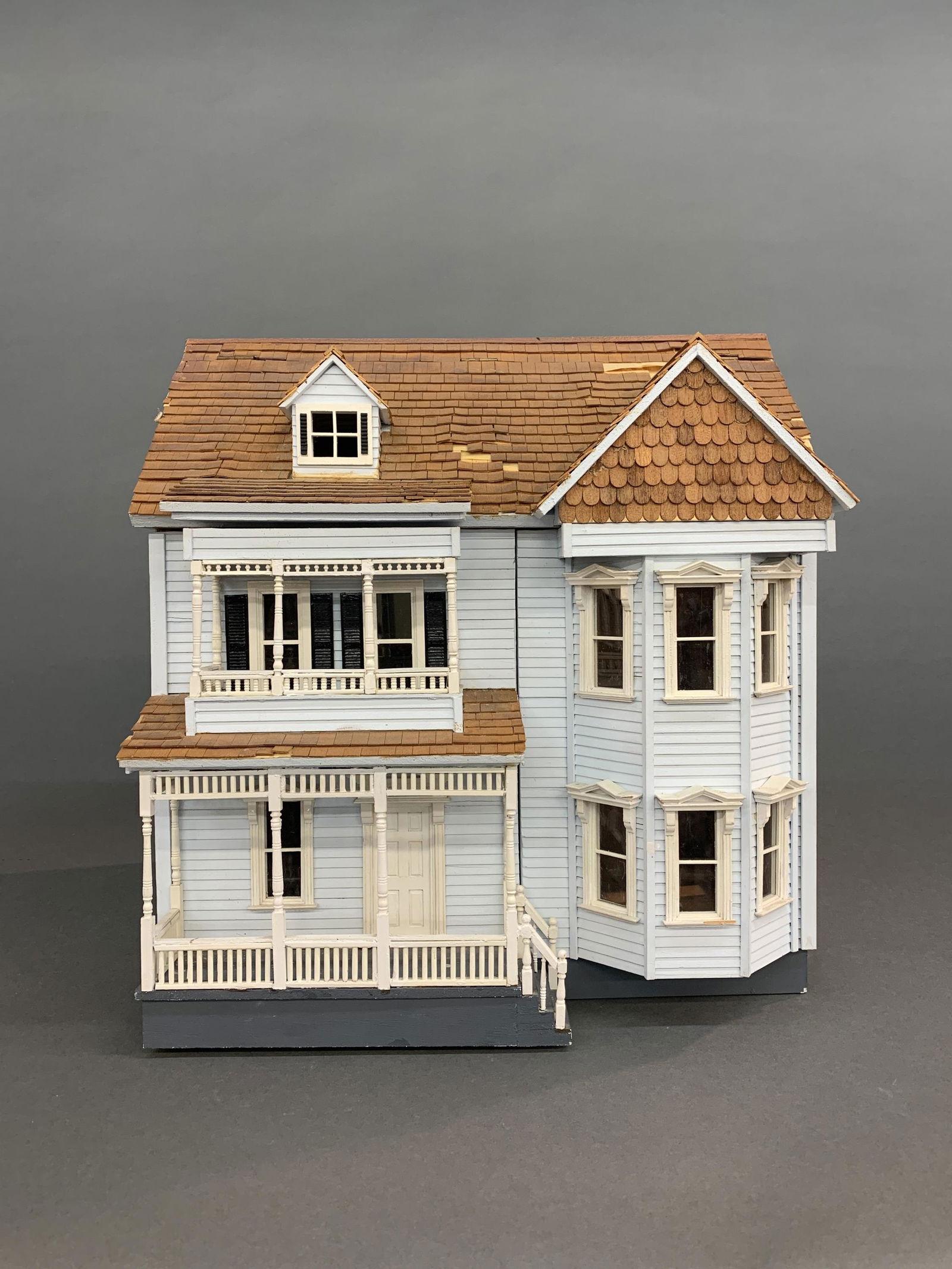 Dollhouse diorama: An unfurnished dollhouse with flip top attic and open front. Missing shingles. 17 3/4" x 16 1/2" x 11 1/2"