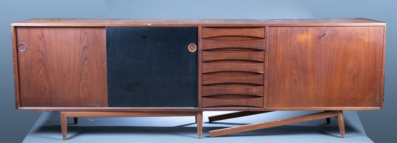 Danish Modern Arne Vodder Mod. 29a credenza.: A Danish Modern Arne Vodder (Danish, 1926-2011) for Sibast Furniture Mod. 29a Teak and lacquered wood credenza. 31 1/2" x 98" x 18 1/2".Condition: One leg bracket separated. Staining and discoloration