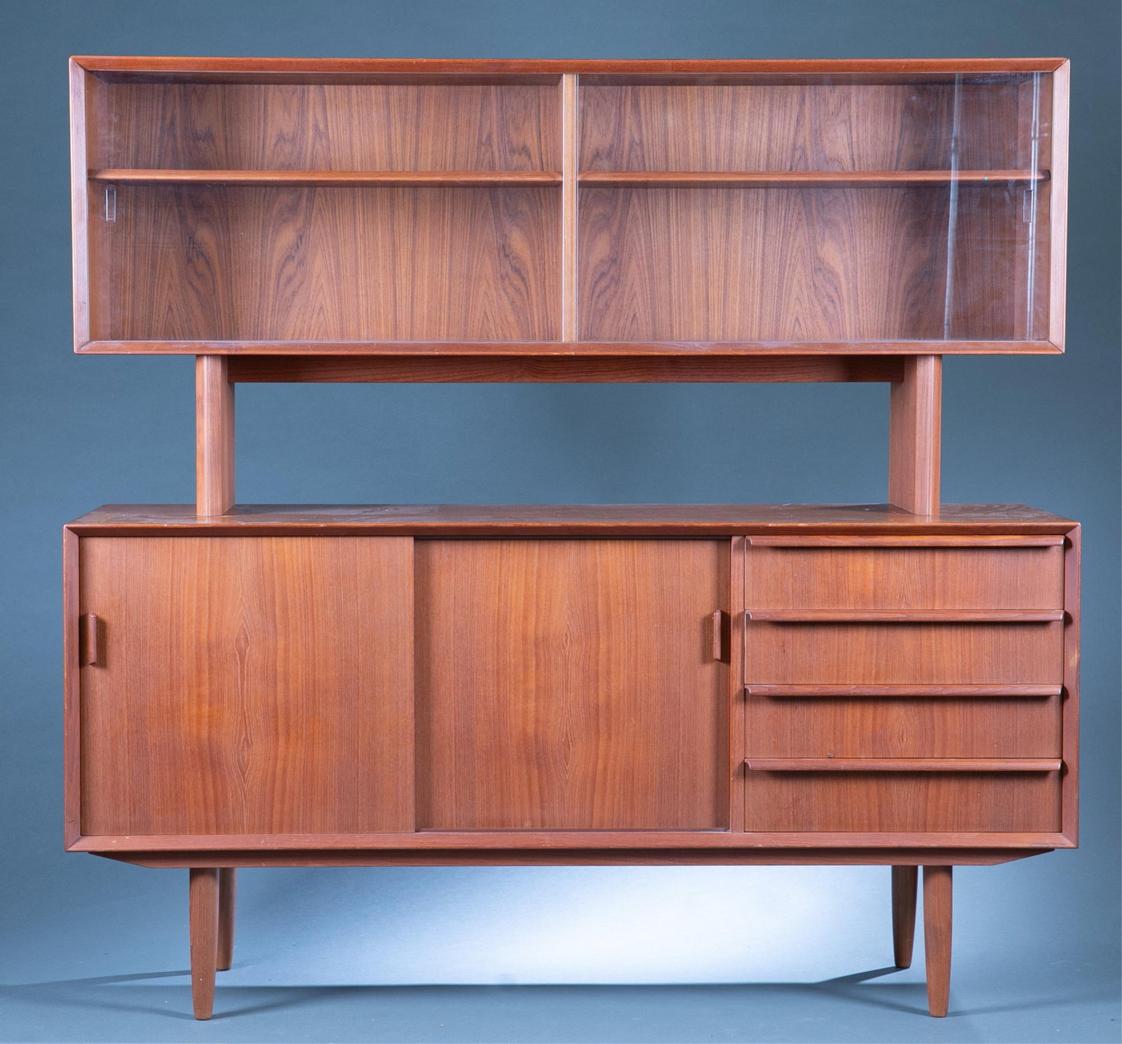 Danish Modern Falster credenza hutch.: A Danish Modern Falster two piece teak credenza hutch. Hutch with two glass sliding doors revealing two shelves over two sliding doors astride four drawers. Marking in left of drawer. 57 1/2" x 60" x 