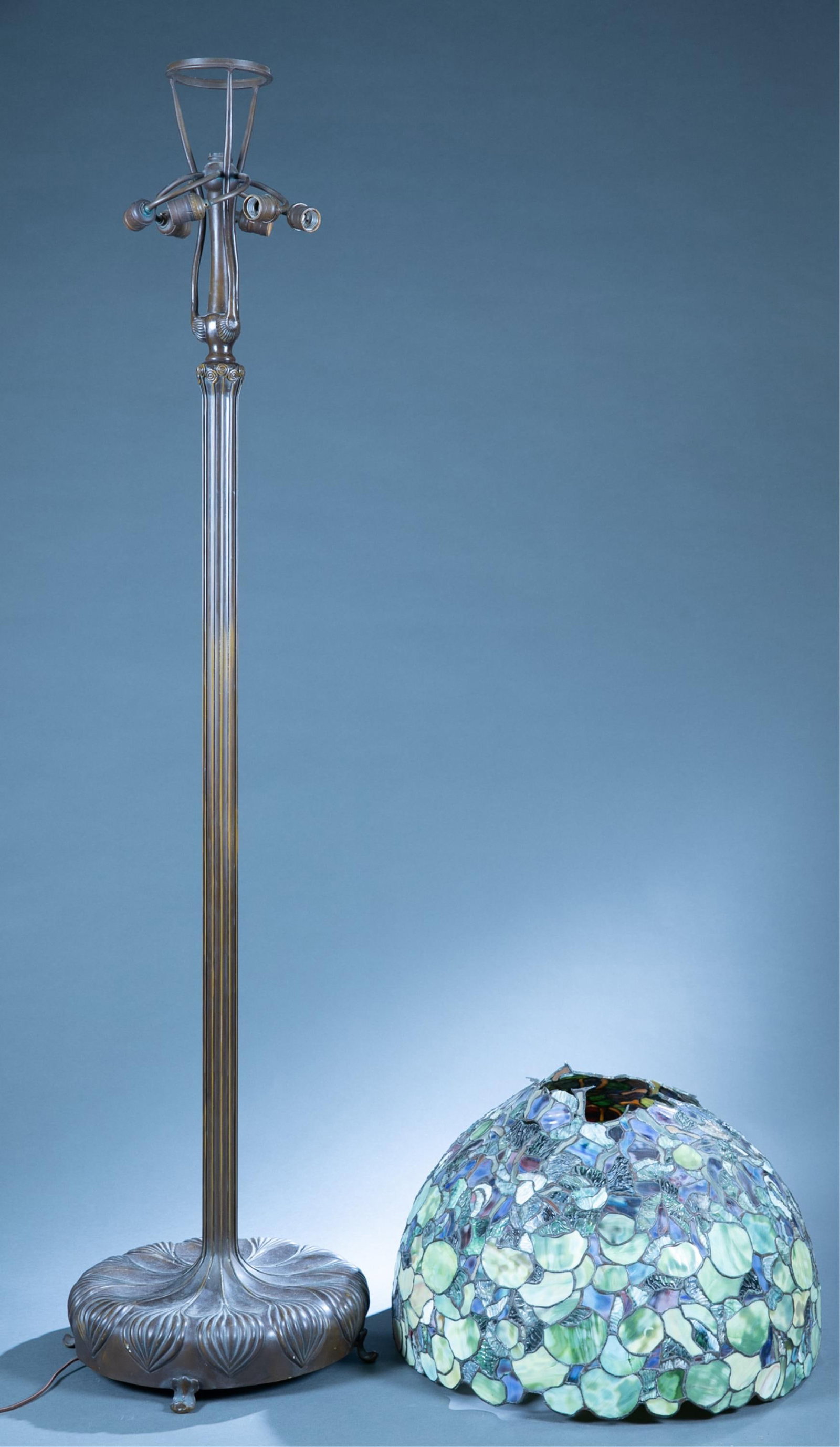 Tiffany Studios style floor lamp.: A Tiffany Studios style floor lamp, 20th Century. Onion base with reeded column ending in decorative scrolls. Blue green leaded glass shade. Lamp: 70" x 17" and shade 15" x 25"Condition: Shade as foun