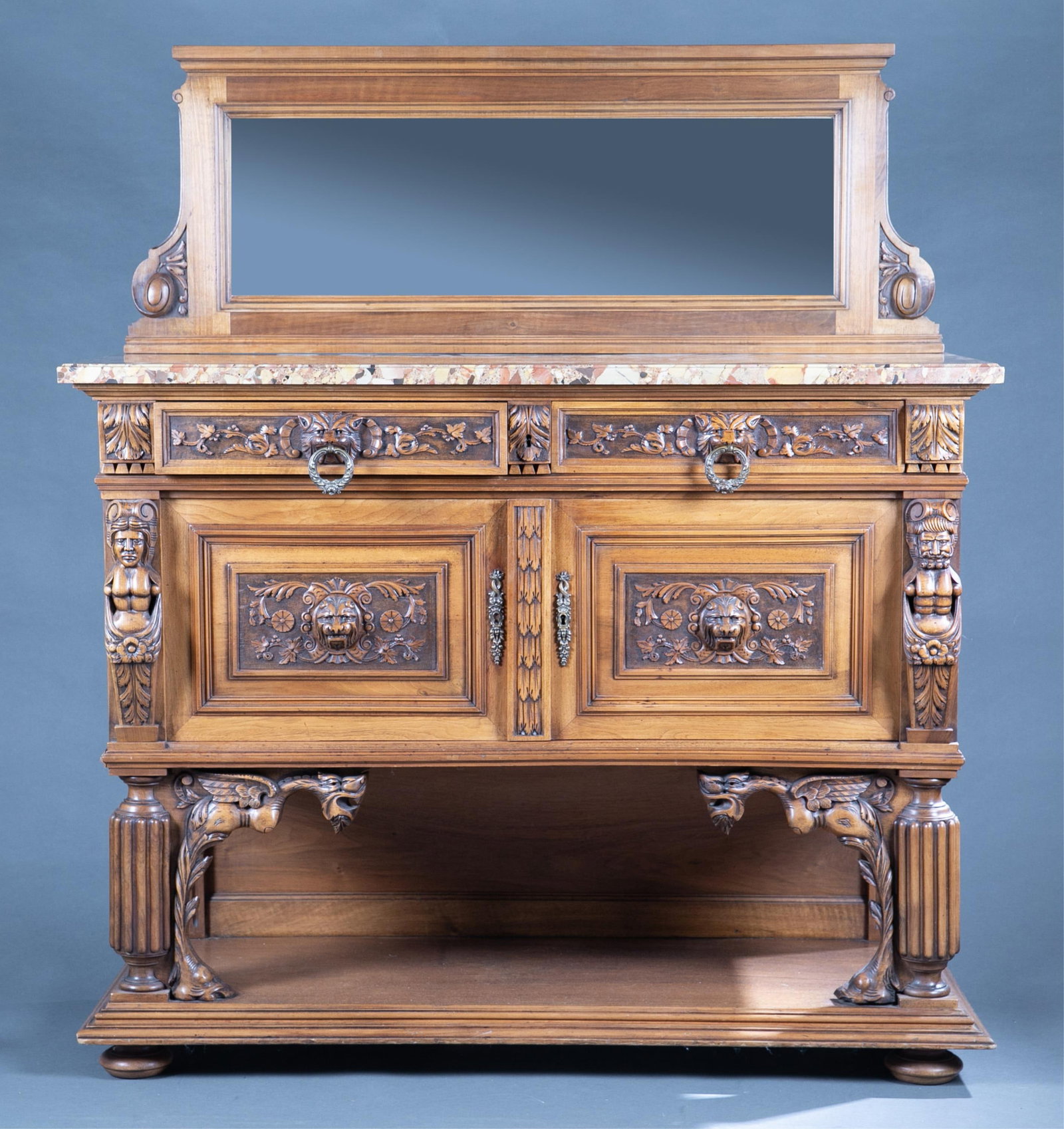 French Renaissance Revival sideboard.: A French Renaissance revival sideboard, Early 20th century. Mirror backslash and marble top. Two drawers with lion mask pulls over two doors with lion masks. Open bottom shelf. 58" x 50 1/2" x 19"