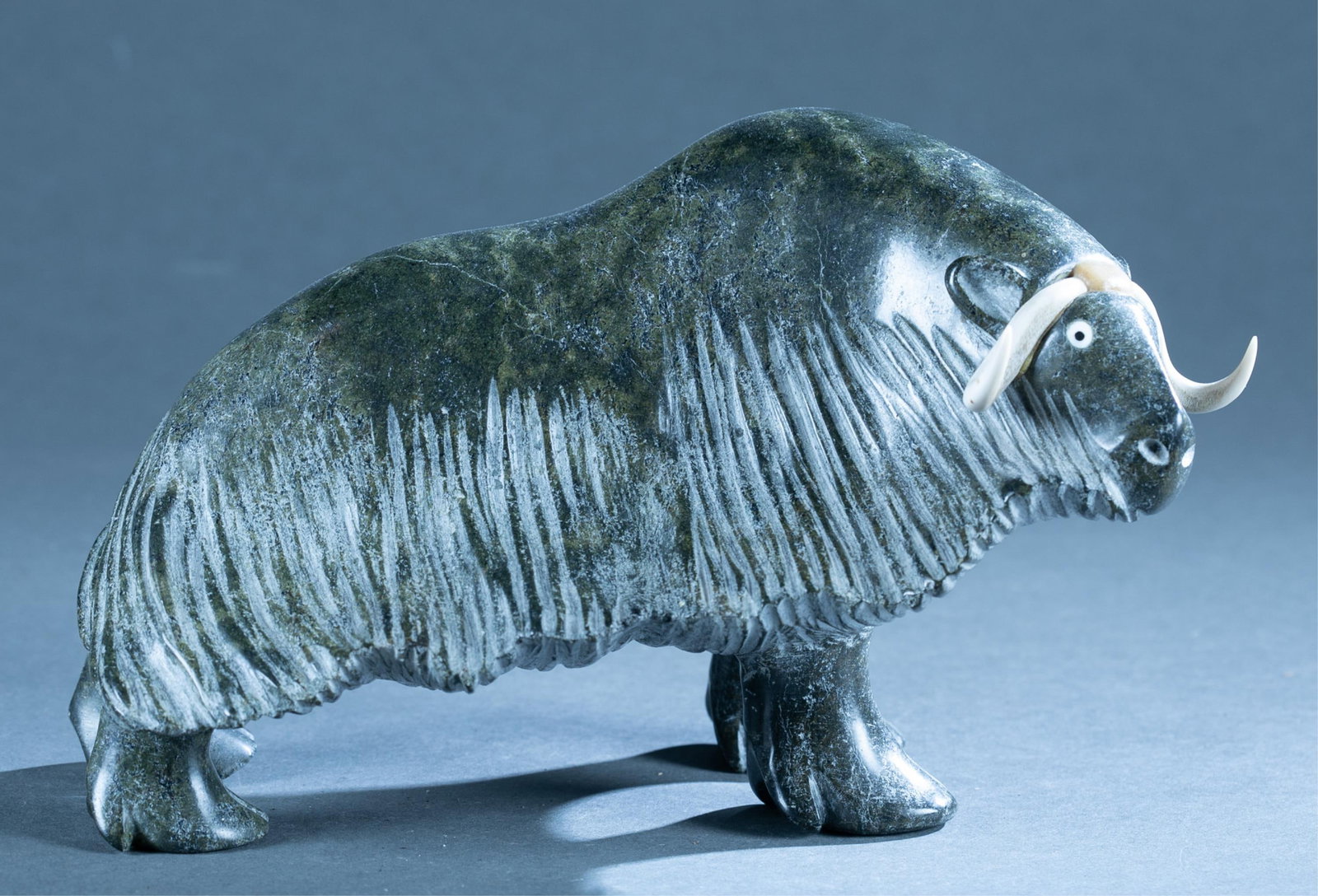 Ipellie, Soapstone musk ox.: Nuveeya Ipellie (Inuit, 1920-2019). A green soapstone sculpture of a musk ox. Initials "NI" on bottom. 6 1/2" x 10" x 5 1/4".