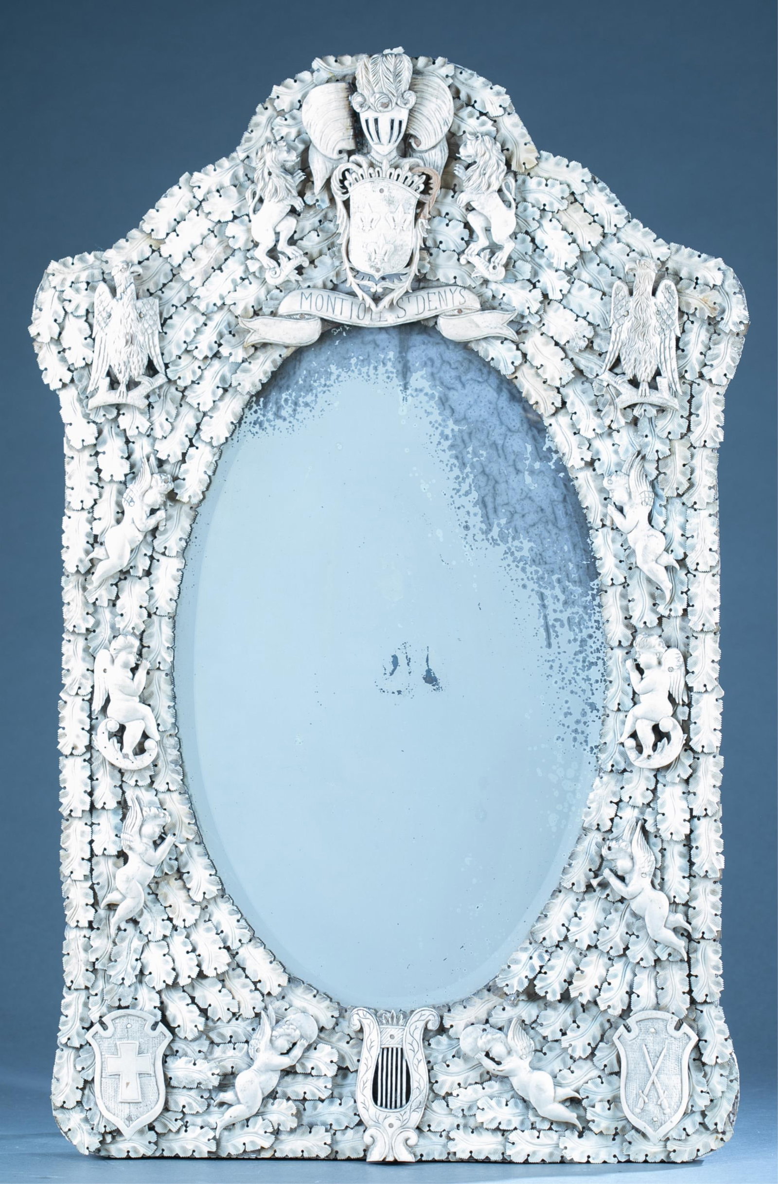 French, Dieppe carved bone mirror.: A French, Dieppe Prisoner of War carved bone mirror, Late 19th Century. Carved foliate design, coat of arms of France flanked by lions with motto "Montjoie Saint Denis," eagles, winged putti, armorial