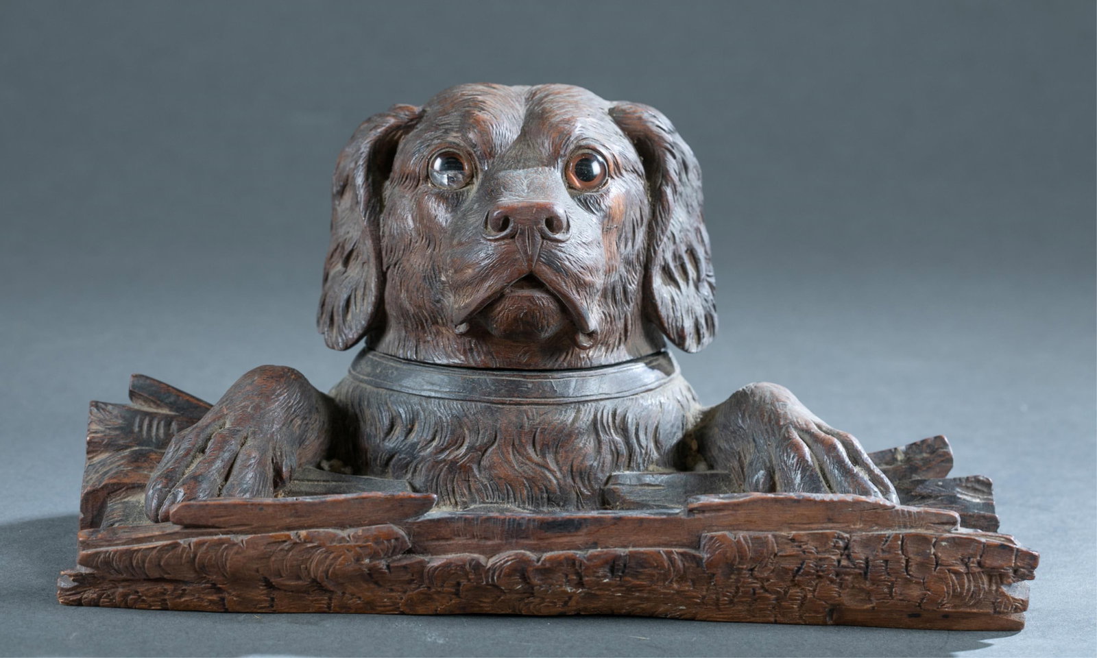 Black Forest dog carved wood inkwell: A Black Forest Setter dog carved wood inkwell, 19th Century. Dog features glass eyes and head lifts to reveal inkwell with log form pen holder. 5" x 11" x 7"Condition: Missing stopper to lid. Damage t
