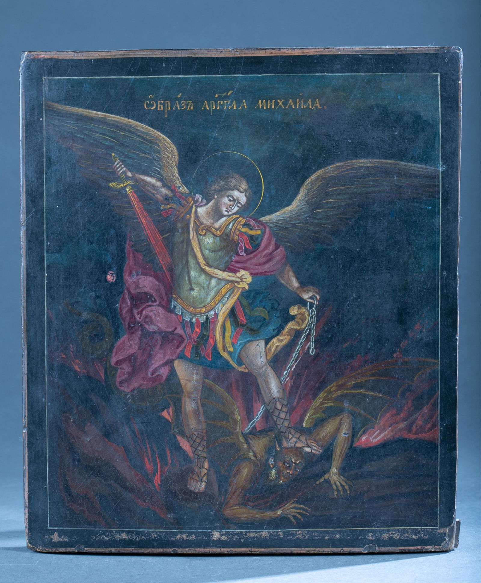 Russian Icon of St Michael the Archangel.: A Russian icon of St Michael the Archangel about to wound Satan at his feet. Tempera on panel. Late 19th century. 14 1/4" x 12".Condition: some damage to edges, craquelure