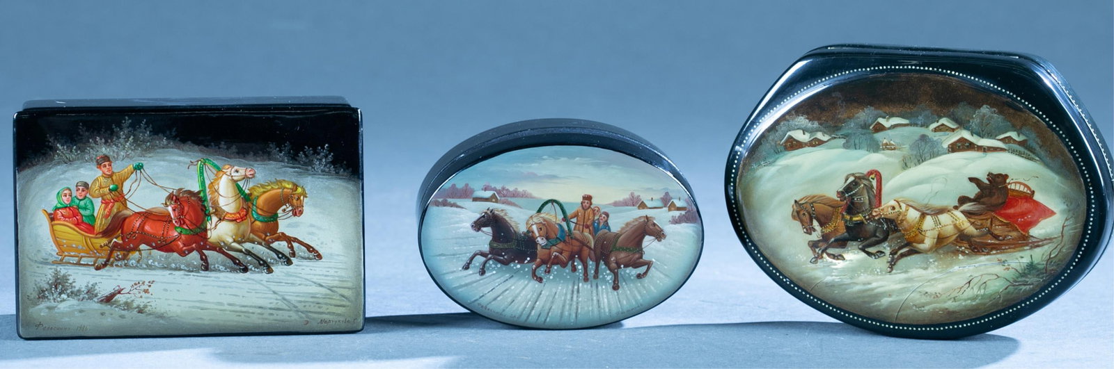 3 Soviet Russian troika lacquer boxes.: A group of three Soviet Russian troika lacquer boxes. ++ Two Fedoskino, signed. 1 3/4" x 5 1/4" x 3 1/2" and 1 6/8" x 4 1/4" x 3" ++ Unsigned box depicting bear in troika. 1" x 6" x 4 1/4"