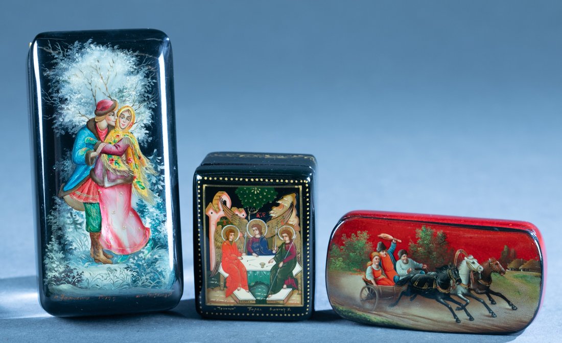 3 Soviet Russian lacquer boxes.: A group of three Soviet Russian lacquer boxes with red interiors. ++ Fedoskino. Young couple.1994. Inscription near edge. 1 1/8" x 4 1/2" x 2 1/4".++ Palekh. Three saints. Inscription near edge. 1 1/4