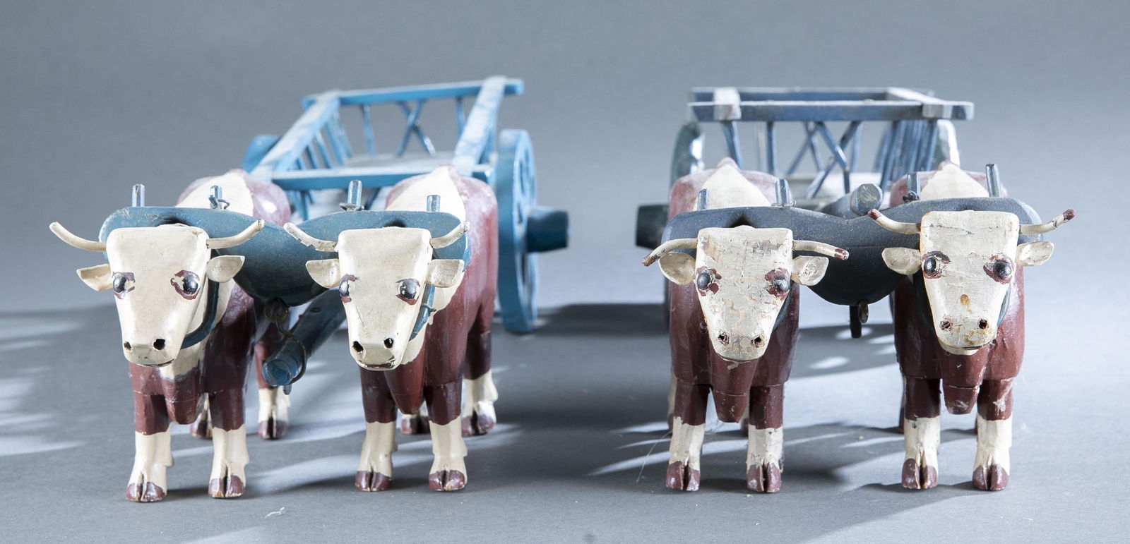 2 yoked oxen with carts: A group of two yoked oxen with carts. American. Painted wood. Unsigned. 5 3/4" x 19 1/2" x 6 1/2"Provenance: The Pete Cecere Folk Art Collection.