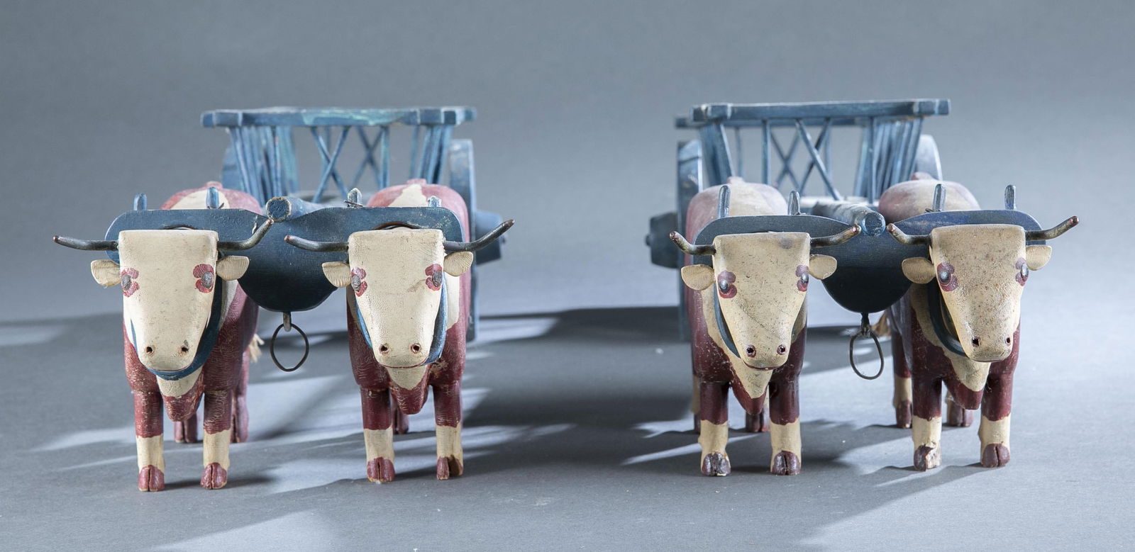 2 yoked oxen with carts: A group of two yoked oxen with carts. American. Painted wood. Unsigned. 5" x 18" x 7 3/4"Provenance: The Pete Cecere Folk Art Collection.