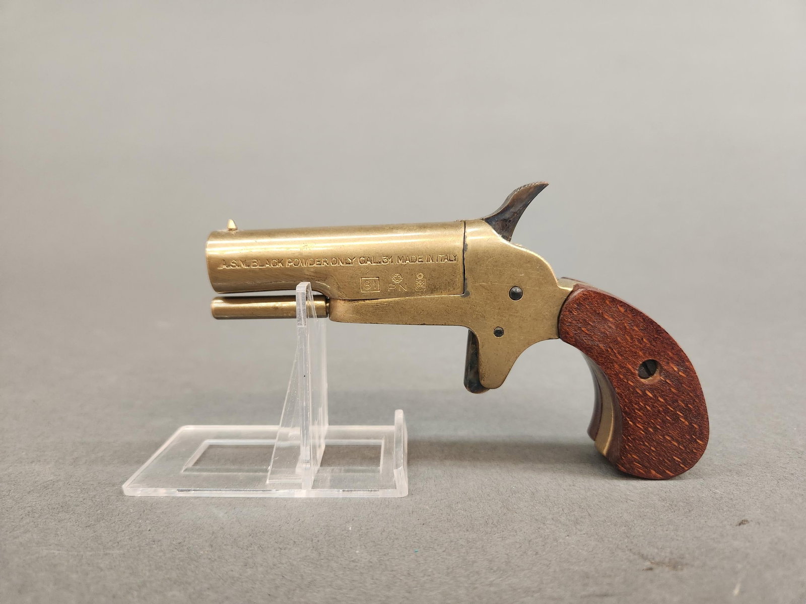 A.S.M. Italian black powder derringer, .31 Cal: An A.S.M. Italian black powder brass derringer, .31 Cal. Swing out barrel with percussion cap place on reverse of breach. 5" overall Condition: Two large divets in interior barrel. Barrel loose.
