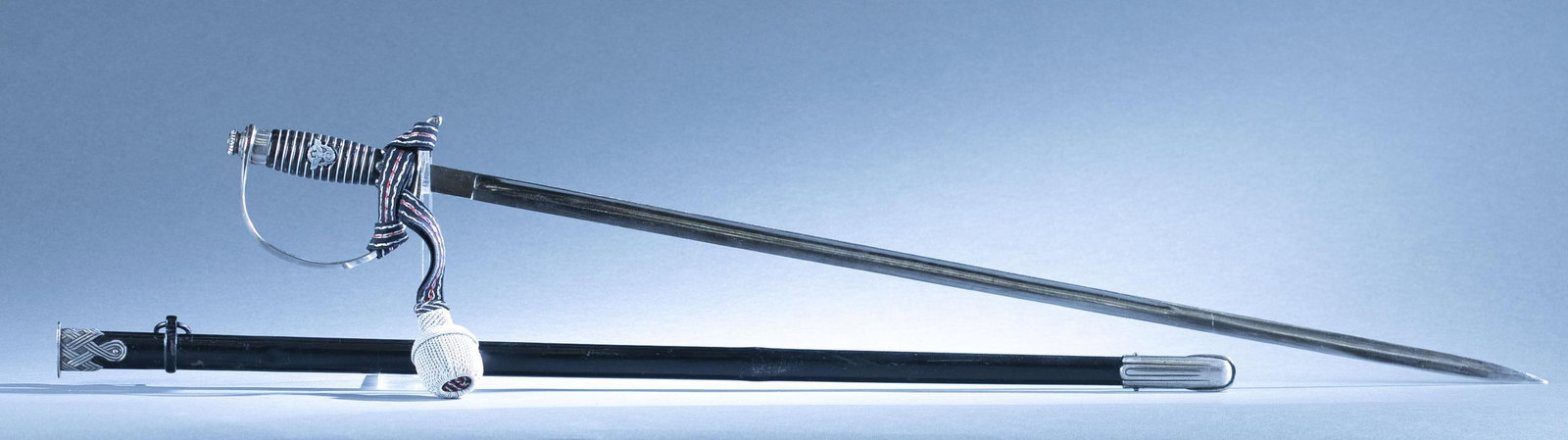 WWII German police sword with scabbard: A WWII German police sword by Carl Eickhorn, Solingen with scabbard and knot. 31 1/2" double edged blade. Marked on ricasso. Nickel silver hilt. Nickel silver mount and painted metal. 37" overall. 32"