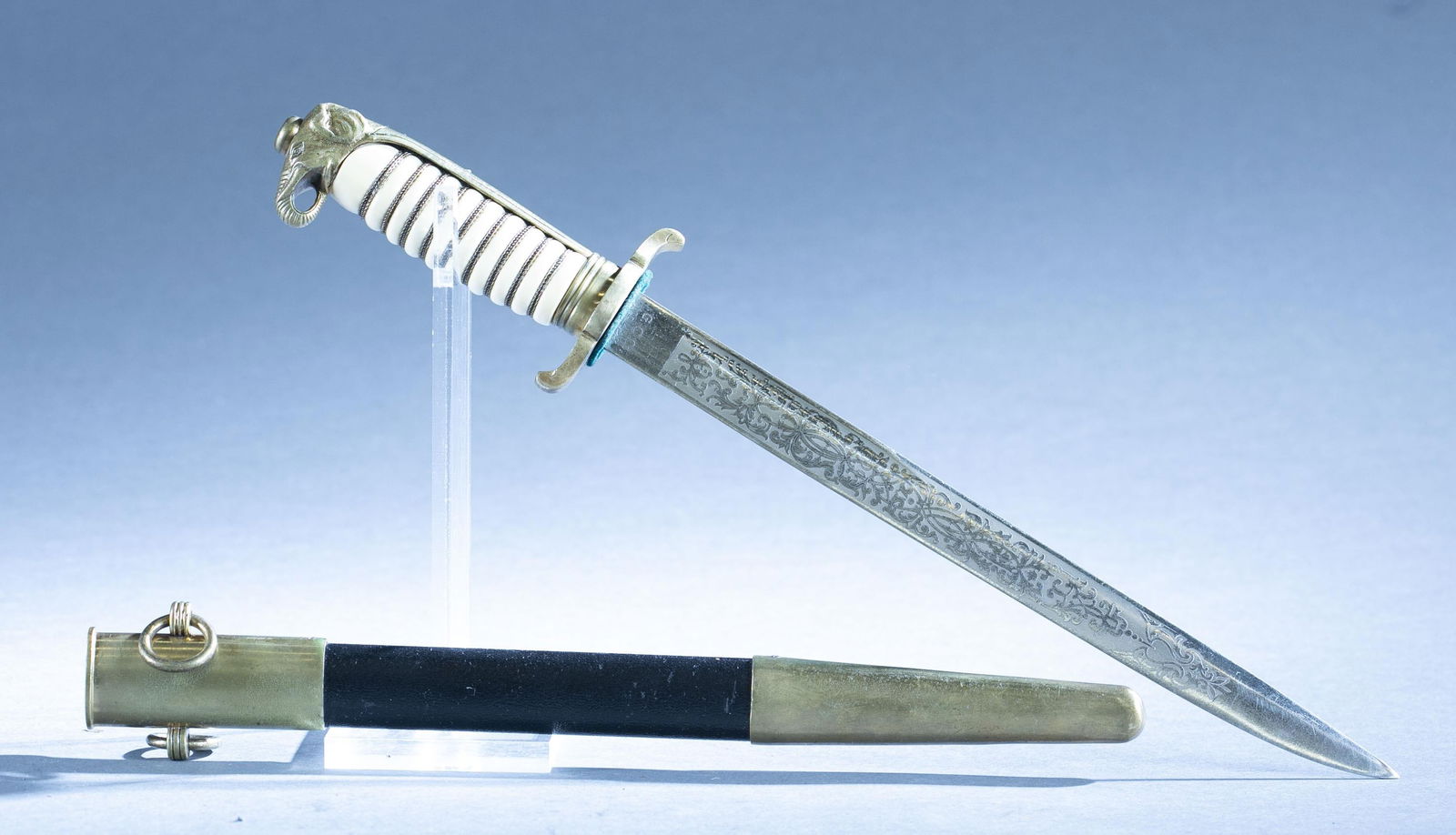 Thai dagger with scabbard: A Thai dagger with scabbard by Guttmann Cutlery Co., Solingen. 10" blade with acid etched blade. Ricasso maker marked and "No. 423." Elephant head pommel. Bakelite grips. 14 1/2" overall. 11 3/4" scab
