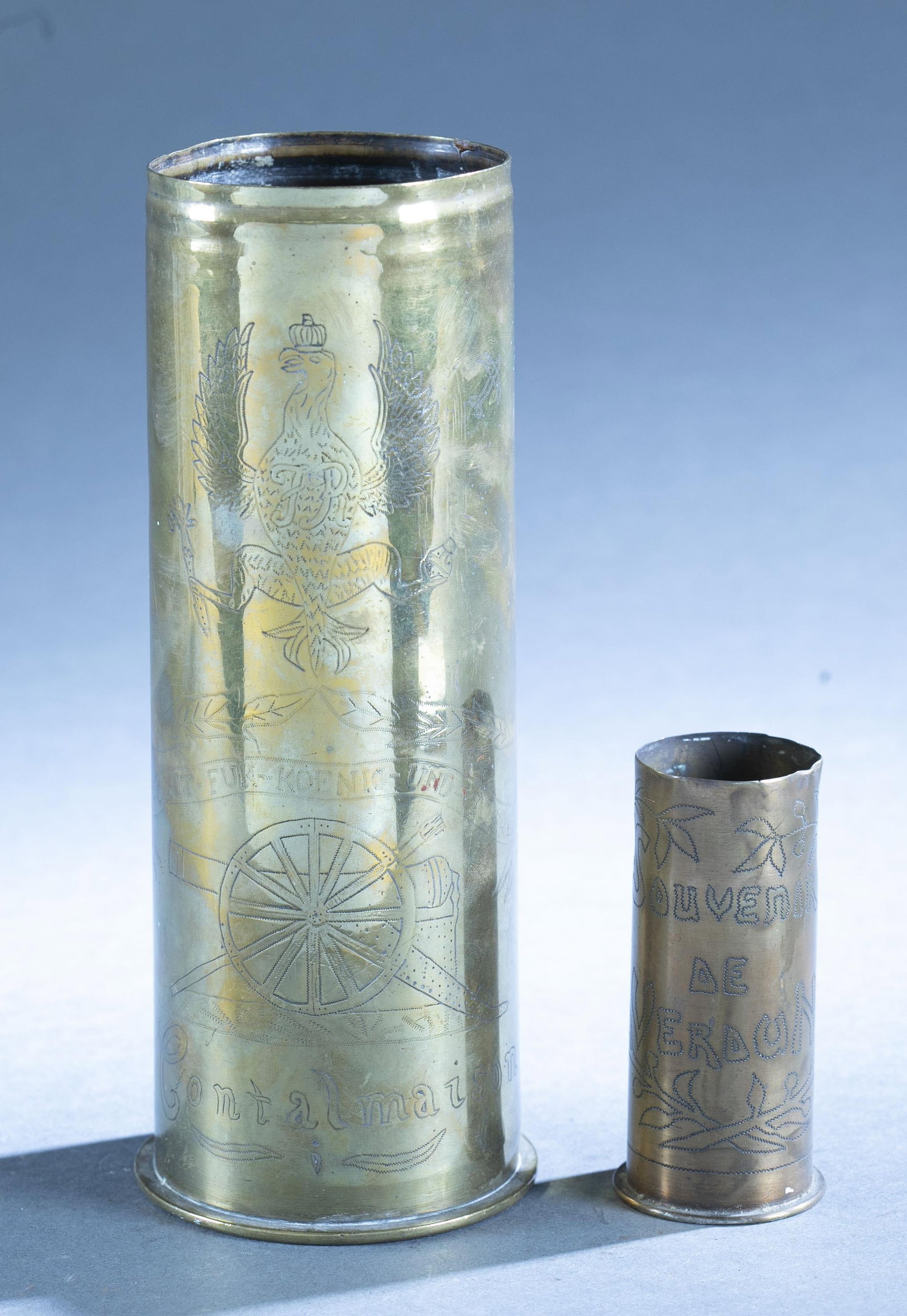 2 WW1 Trench Art shells: A group of two WW1 Trench Art shells. ++ 1915 German shell with etched with Prussian eagle and motto over cannon over "Contalmaison." 9" x 3 1/2" ++ Shell etched "Souvenir/ de / Verdun." 4" x 1 7/8"