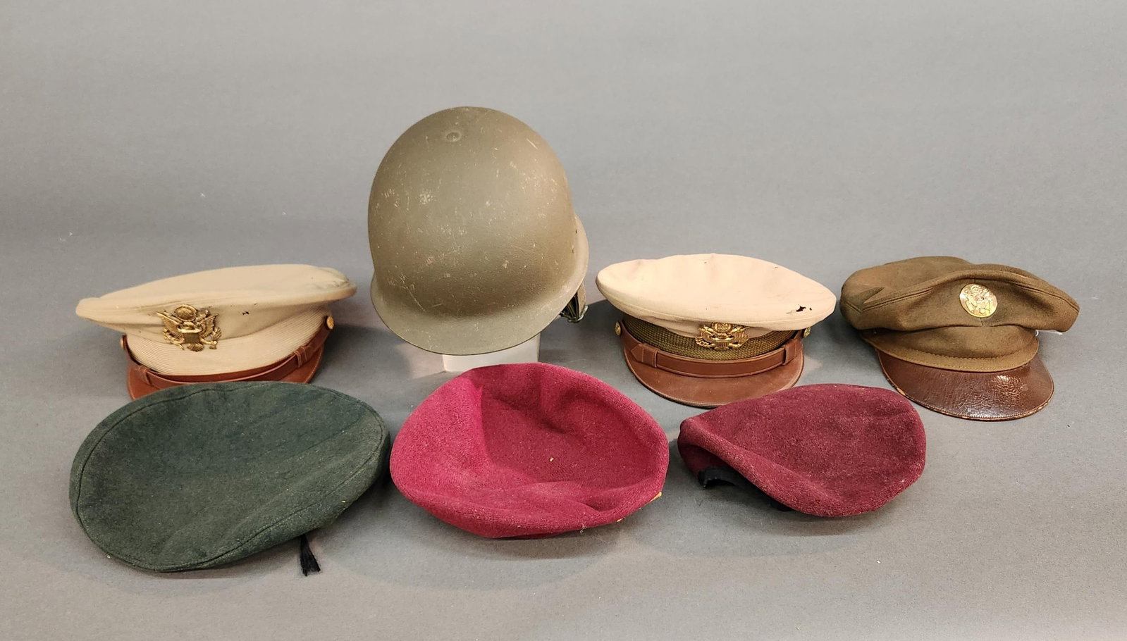 U.S. and European hats and helmets: A group of WWII and Cold War U.S. and European hats and helmets. ++ West German Bundeswehr M1956 helmet with M1931 leather liner. ++ Two maroon berets for 52nd Infantry Regiment. One with Distinguishe