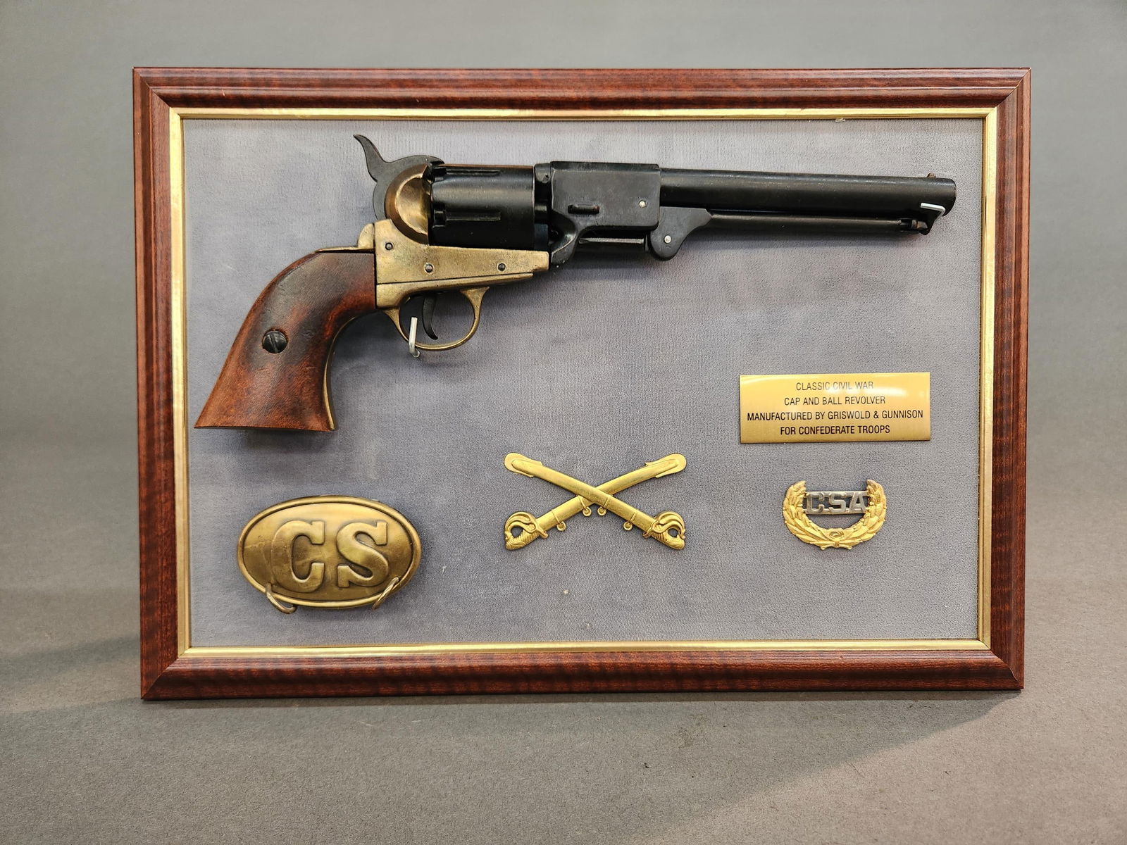 Replica CSA Denix BKA 98 revolver and insignia: A replica Confederate States of America Denix BKA 98 Griswold & Gunnison revolver, replica CSA belt buckle, insignia, and cavalry cap insignia. 11 1/2" x 16 1/2"