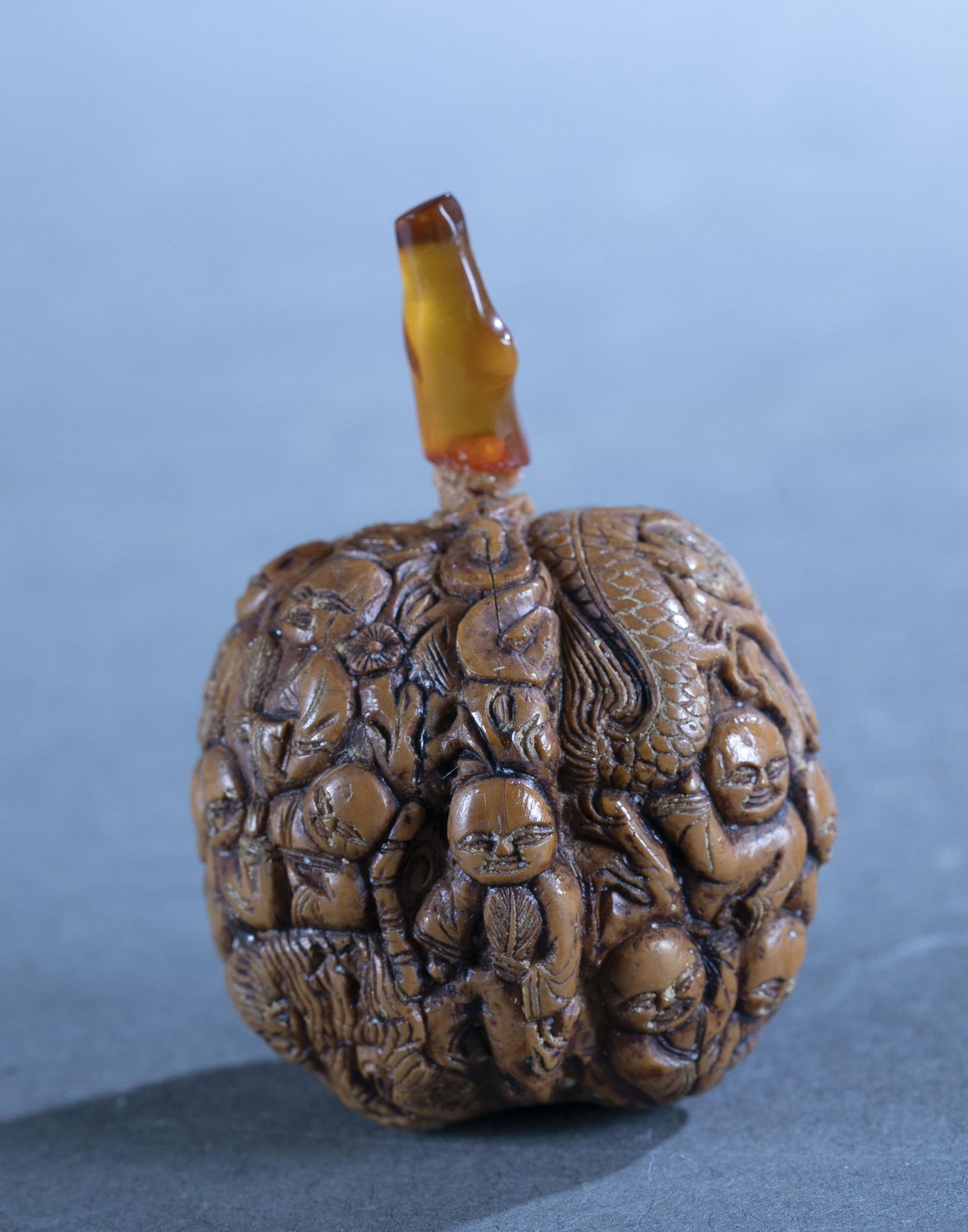 Chinese carved walnut snuff bottles.: A Chinese carved walnut snuff bottles with amber stopper. 1.5" x 1.6" x 1.4".Stopper separated.