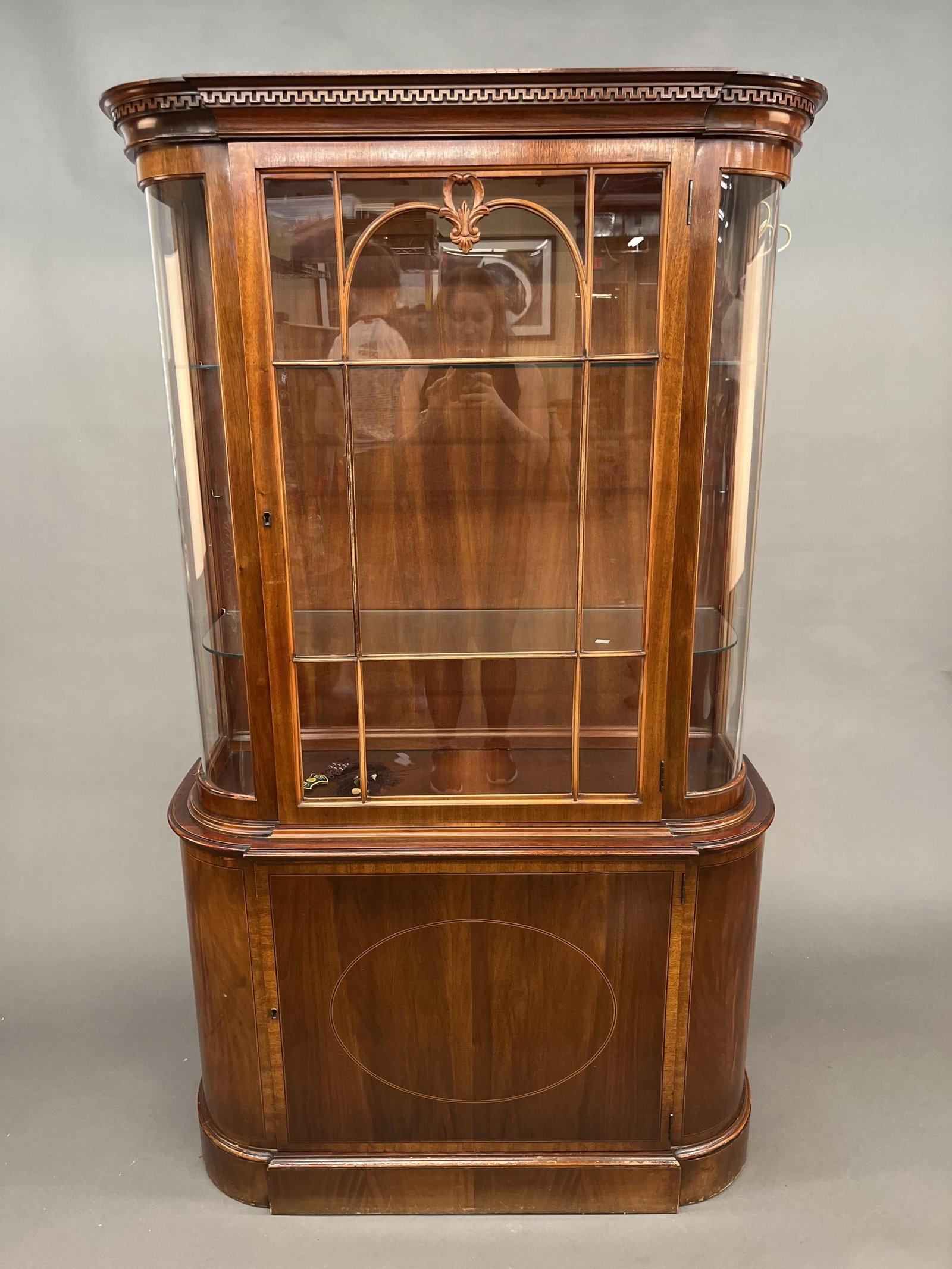 Display cabinet: A mahogany and walnut display cabinet. Greek key fretwork over one glass door with two shelves over one door. 69 1/2" x 41 1/2" x 15" . Provenance: From the estate of U.S.M.C. Four Star General Alfred
