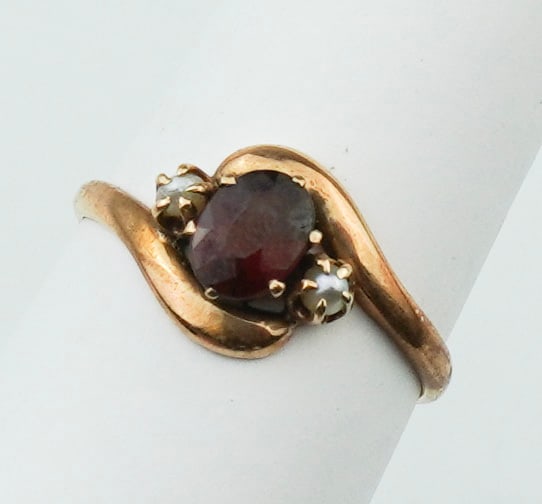 14KYG Garnet & Pearl Ring: A 14KYG Garnet & Pearl Ring size 6, prong set round faceted garnet approx. 5.0mm, two prong set seed pearls approx. 1.0mm, gross weight approx. 1.15dwt. Provenance: From the estate of U.S.M.C. Four St