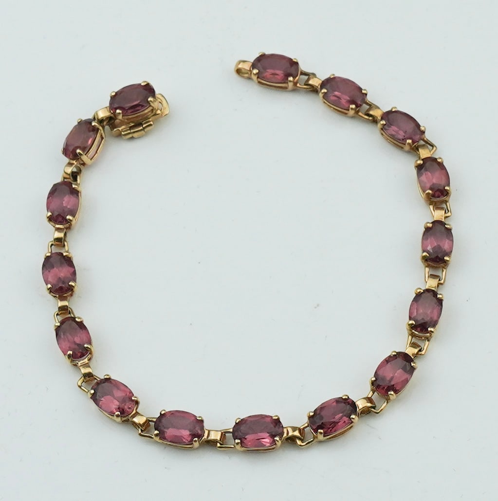 14KYG Garnet Bracelet: A 14KYG Garnet Bracelet approx. 6.0 inches with 16 prong set oval faceted garnets approx. 5.0mm x 4.0mm, stamped and tested 14K yellow gold, gross weight approx. 3.40dwt. Condition: missing an "o" rin