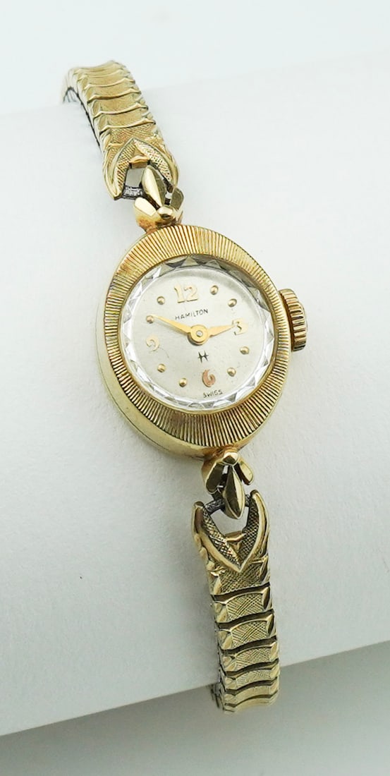 Vintage 14KYG Ladies Hamilton Watch: A Vintage 14KYG Ladies Hamilton Watch in slight oval shape with etched bezel, silver dial with gilt hands, numerals and markers, manual wind movement, stamped and tested 14K yellow gold case, stretch 