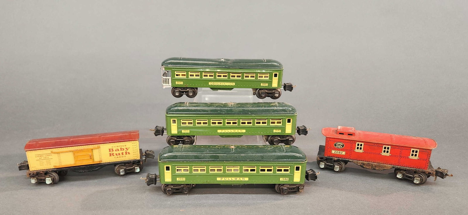 5 Prewar Lionel tin cars: A group of five Prewar Lionel tin cars. Including two No. 2640 pullman cars, 2641 observation car, No. 2669 Baby Ruth box car, and No. 2682 caboose. Includes damaged boxes. Condition: Boxcar and caboo