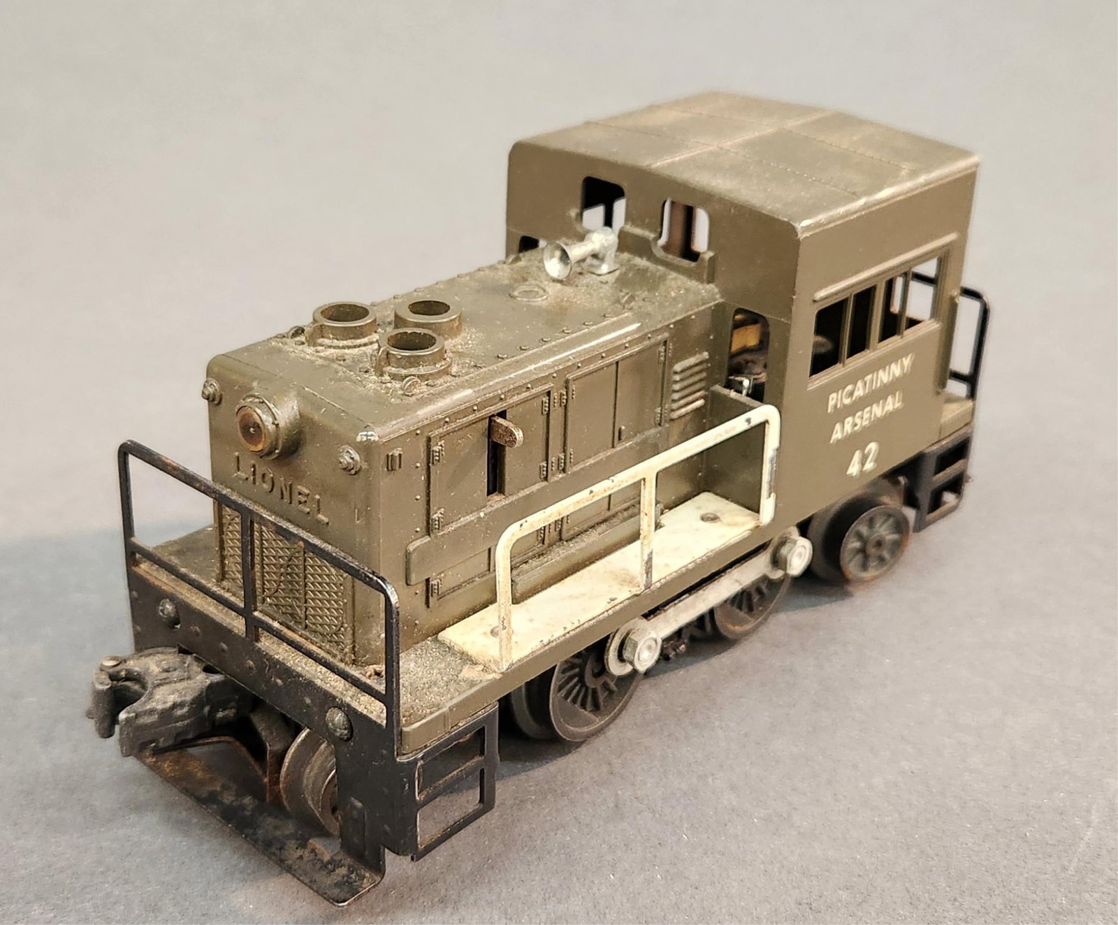 Postwar Lionel O Gauge No. 42 Picatinny Arsenal: A postwar Lionel O Gauge No. 42 The Picatinny Arsenal gas turbine switcher unit. 3 1/2" x 7 1/2" x 2 1/2" Condition: Body in good condition. Wear on edges and scratches. Oxidation on some metal. Flaki
