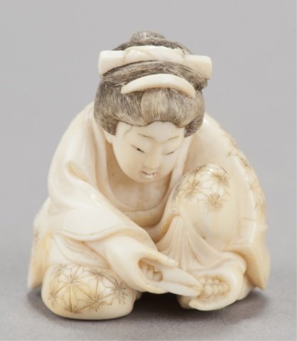 An ivory shunga netsuke of a woman cutting her toe: Kikugawa family, possibly Toun, Tokyo, Mid 19th century. , Mid 19th century. Sits with her left knee raised as she intently cuts a toenail on her left foot, patches of patination especially on the bac