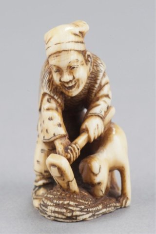An ivory netsuke of Hanasaka Jiji raking gold coin: By Chikuyosai Tomochika 2nd, Tokyo, Mid 19th century. , Mid 19th century. Raking through a pile of gold coins with a dog by his side. Signed on the back in a wavy reserve, Tomochika. The oban coin clo