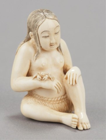 An ivory netsuke of awabi diver and crab.: Chomin, Tokyo, Late 19th century. Seated in her grass skirt sitting with a slight smile on her face looking at a crab that sits on her right wrist, her hair reinforced with black ink and a slight touc