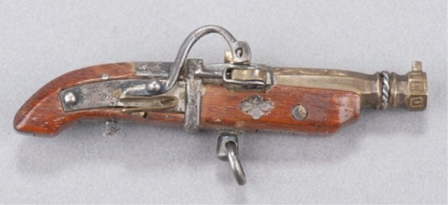 A wood netsuke of a Portuguese gun.: Masamitsu, c.1850. The stock of cherry, the barrel in brass with a hexagonal end to the muzzle, the finishings are steel (?) and silver. The barrel and the finishings are chased with a tendril design 