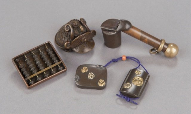 A group of four metal netsuke.: Mid 19th century. The first, a copper working Soroban(Abacus), the inner frame is sentoku, and the counters are iron. 1 3/8in (3.4cm). The second, a bronze samurai helmet ash tray of the type made by 