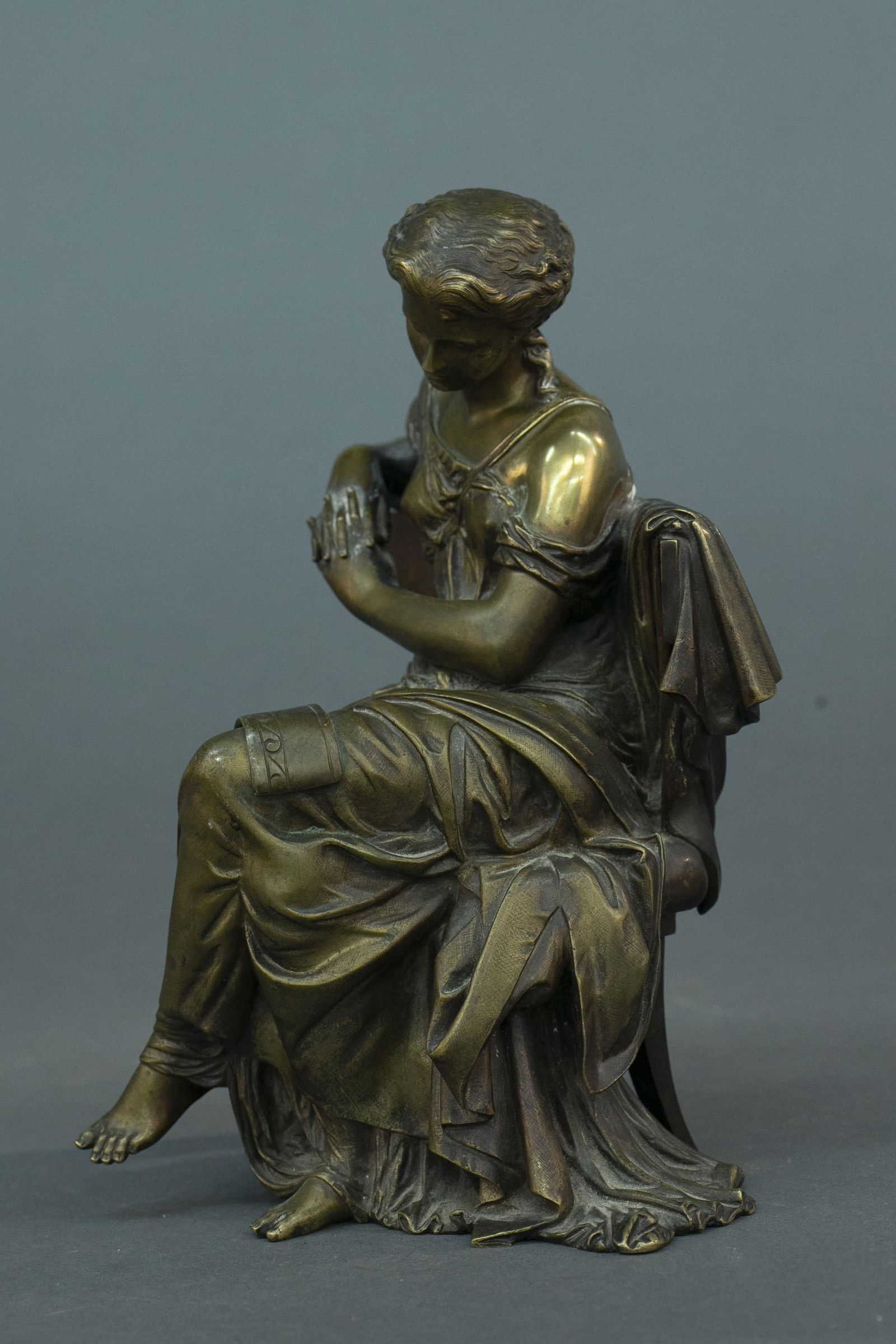 After Moreau, seated woman, bronze: After Auguste Moreau (France, 1834-1917) bronze statue of a seated lady with rolls of fabric. Signed Moreau on back of chair. 11 1/2" x 9"