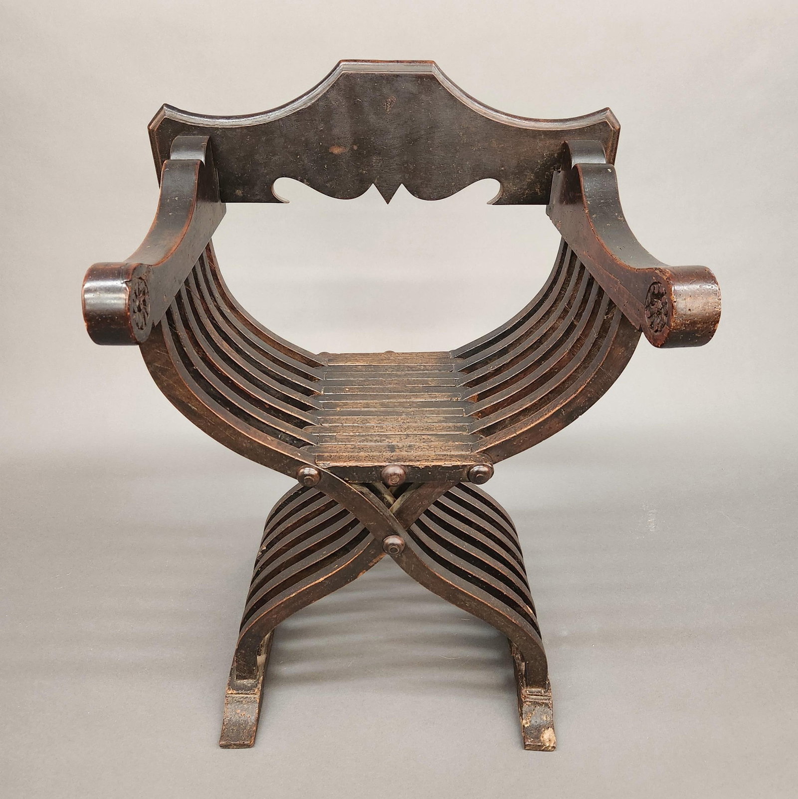 Italian Renissance Savonarola walnut chair: An Italian Renissance Savonarola walnut folding chair, 16th century. Later replaced back panel. Floral rosette in arm. 7 over 7 slats. 37 1/4" x 28" x 21" Condition: Heavy wear. Worm damage particular