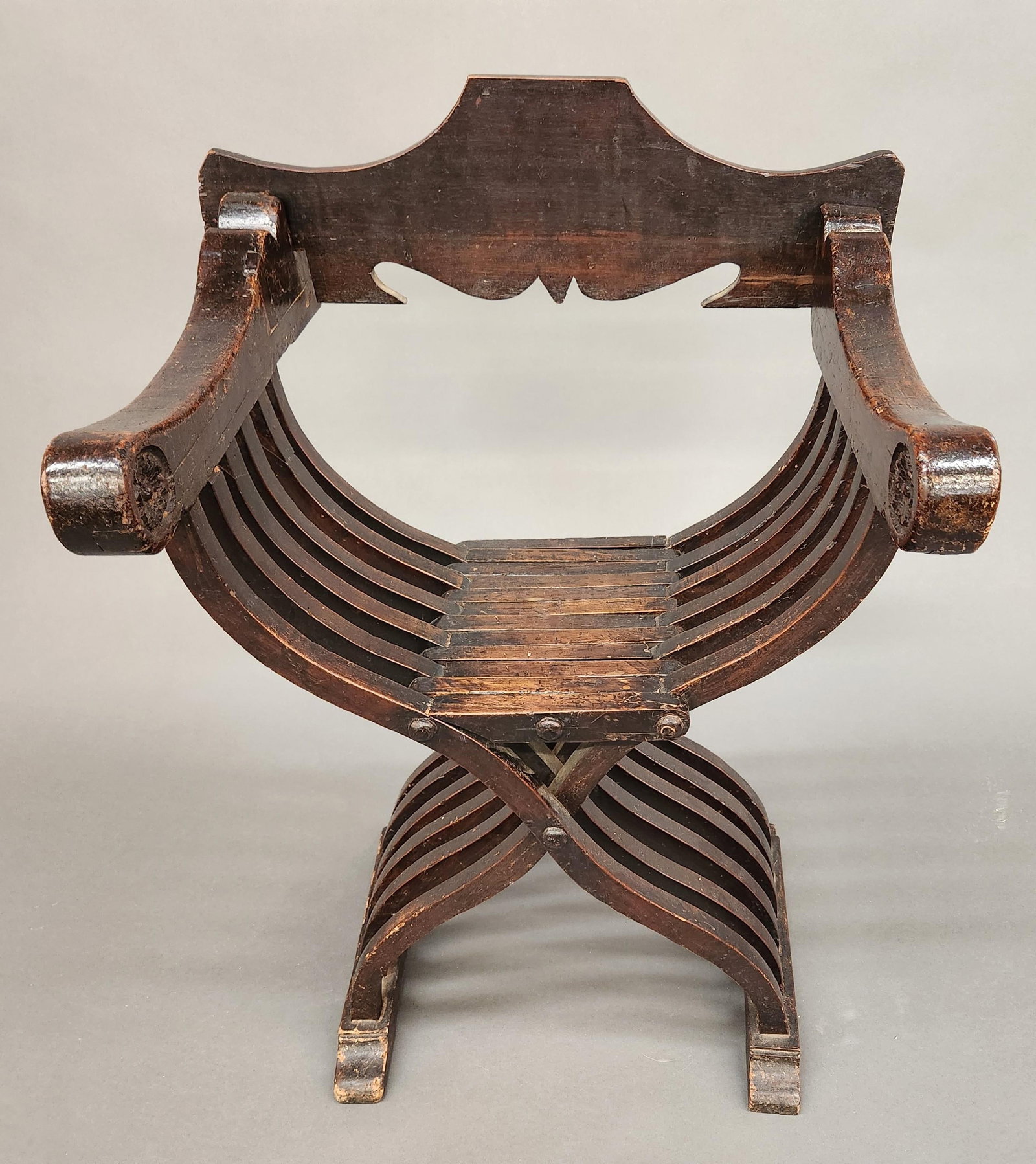 Italian Renissance Savonarola walnut chair.: An Italian Renissance Savonarola walnut folding chair, 16th century. Later replaced back panel. Floral rosette in arm. 6 over 7 slats. 36 1/2" x 26 1/2" x 21". Condition: Heavy wear. Worm damage. Brea