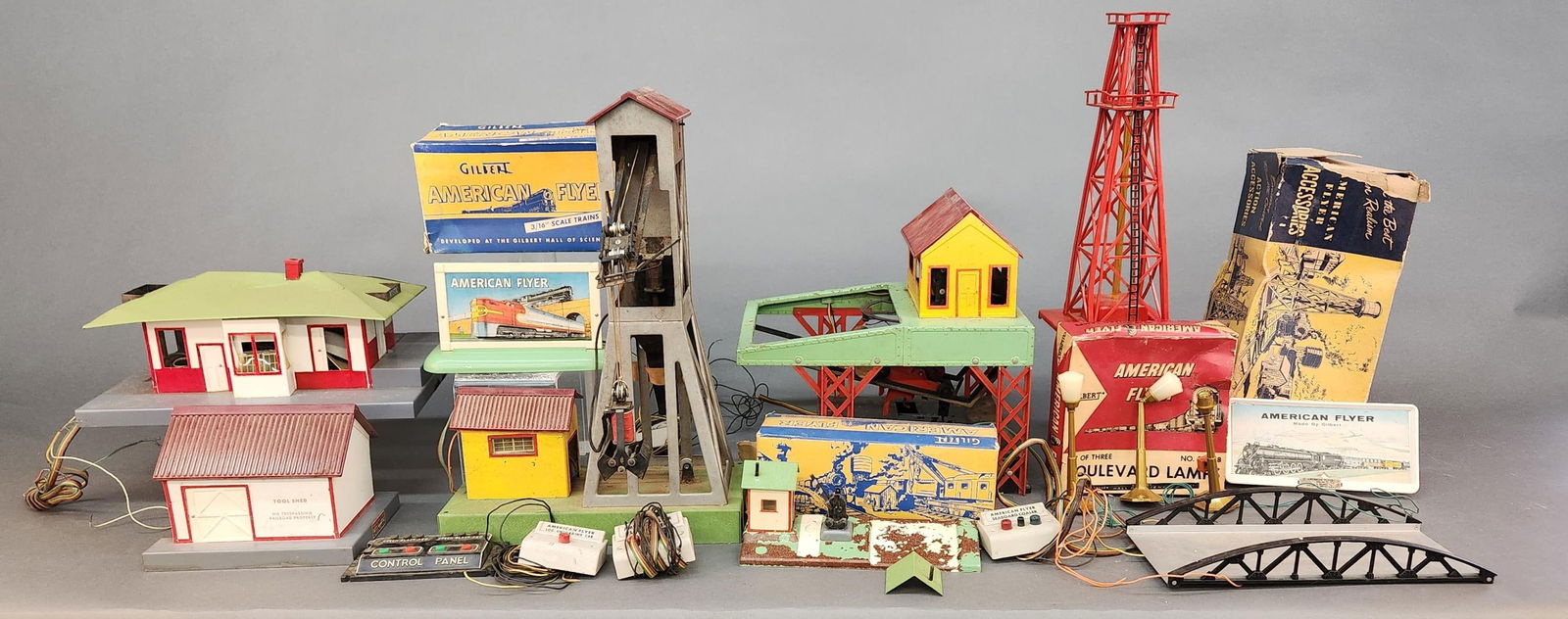 American Flyer accessories: A group of American Flyer accessories. No. 566 Whistling Billboard in box with remote, No. 571 Truss Bridge, No. 585 Tool Shed, No. 591 Crossing gate with box, No. 751 Log Loader with remote,
