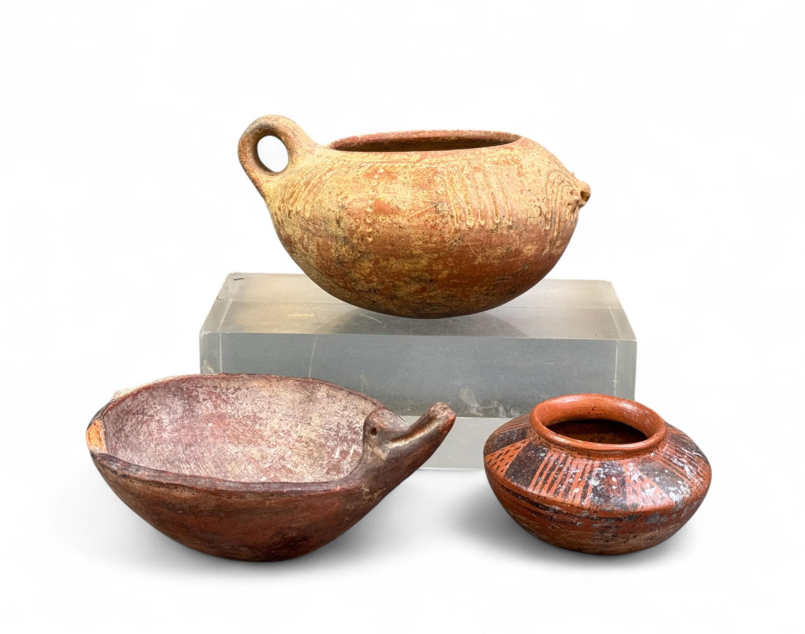 3 Pre-Columbian vessels.: A group of three Pre-Columbian redware pottery vessels. Smallest: 2 1/8" x 3 5/8". Largest: 3 3/8" x 6 1/4". Condition: Chipped rim, abrasions, and surface dirt. Provenance: From the collection of Bru
