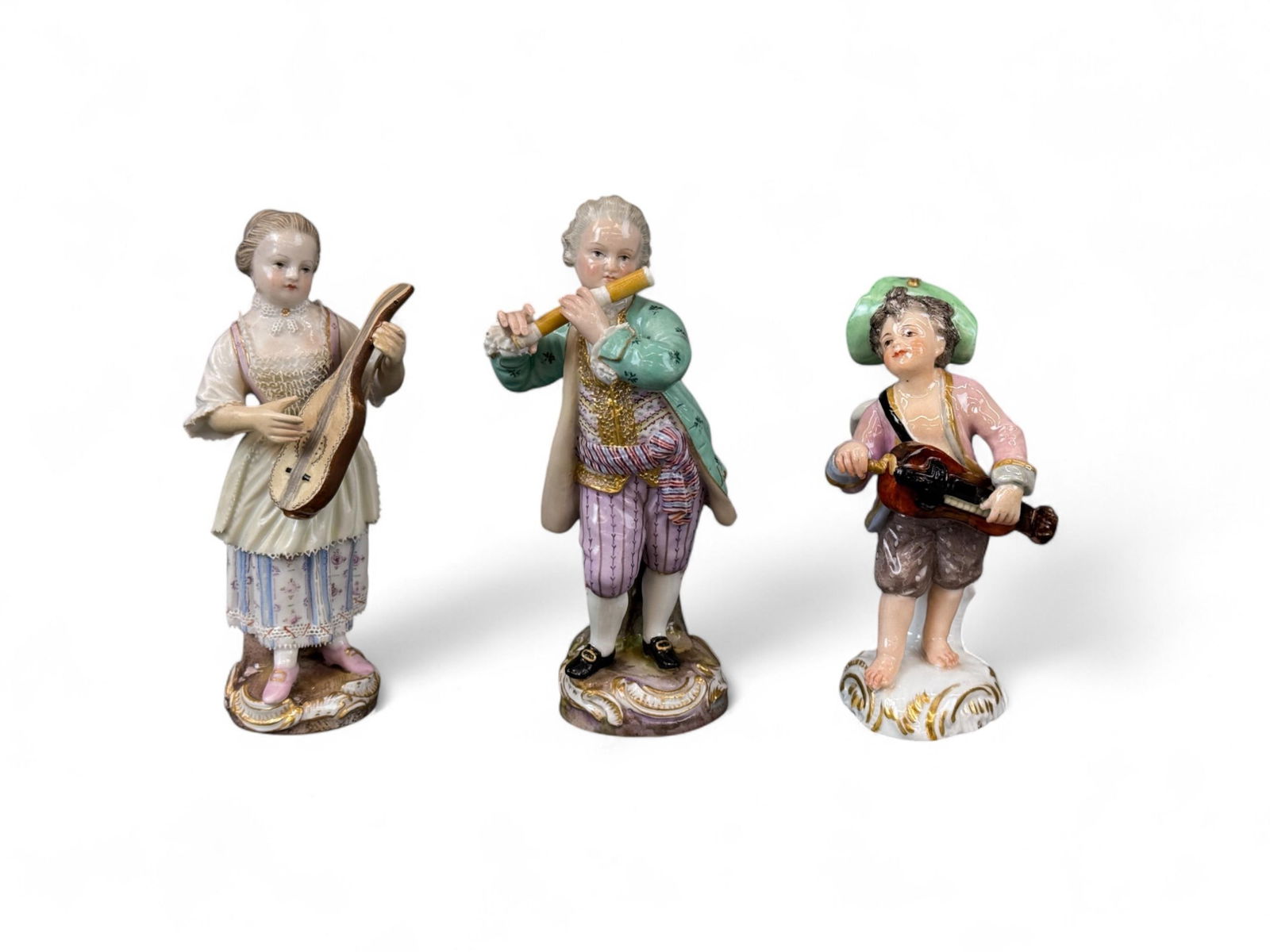 3 Meissen musical figures.: A group of three Meissen musical figures. Marked on bottom. Smallest: 4 1/8" x 2 1/4". Largest: 5" x 2 1/2". Condition: Light pitting, some discoloration, one missing finger, damage to lace trim of cl