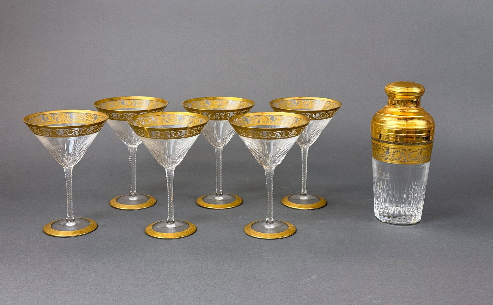 St. Louis "Thistle" cocktail shaker & 6 glasses: A St. Louis "Thistle" gilt crystal Cobbler cocktail shaker and six footed cocktail glasses. Acid marked on base. All have original sticker. Shaker: 8 1/4" x 3 1/2". Cocktail: 6 1/2" x 4 1/2". Conditio