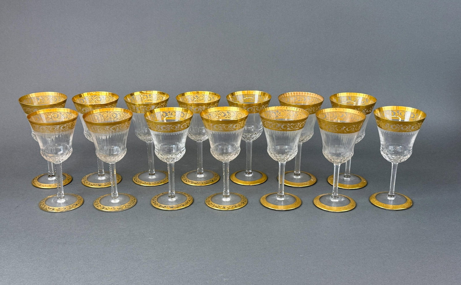 14 St. Louis "Thistle" Burgundy wine glasses.: A group of fourteen St. Louis "Thistle" gilt crystal Burgundy wine glasses. Eight open band foot and six solid band foot. Acid marked on base. 6 3/4" x 3 1/4". Condition: 9 have wear on rim.