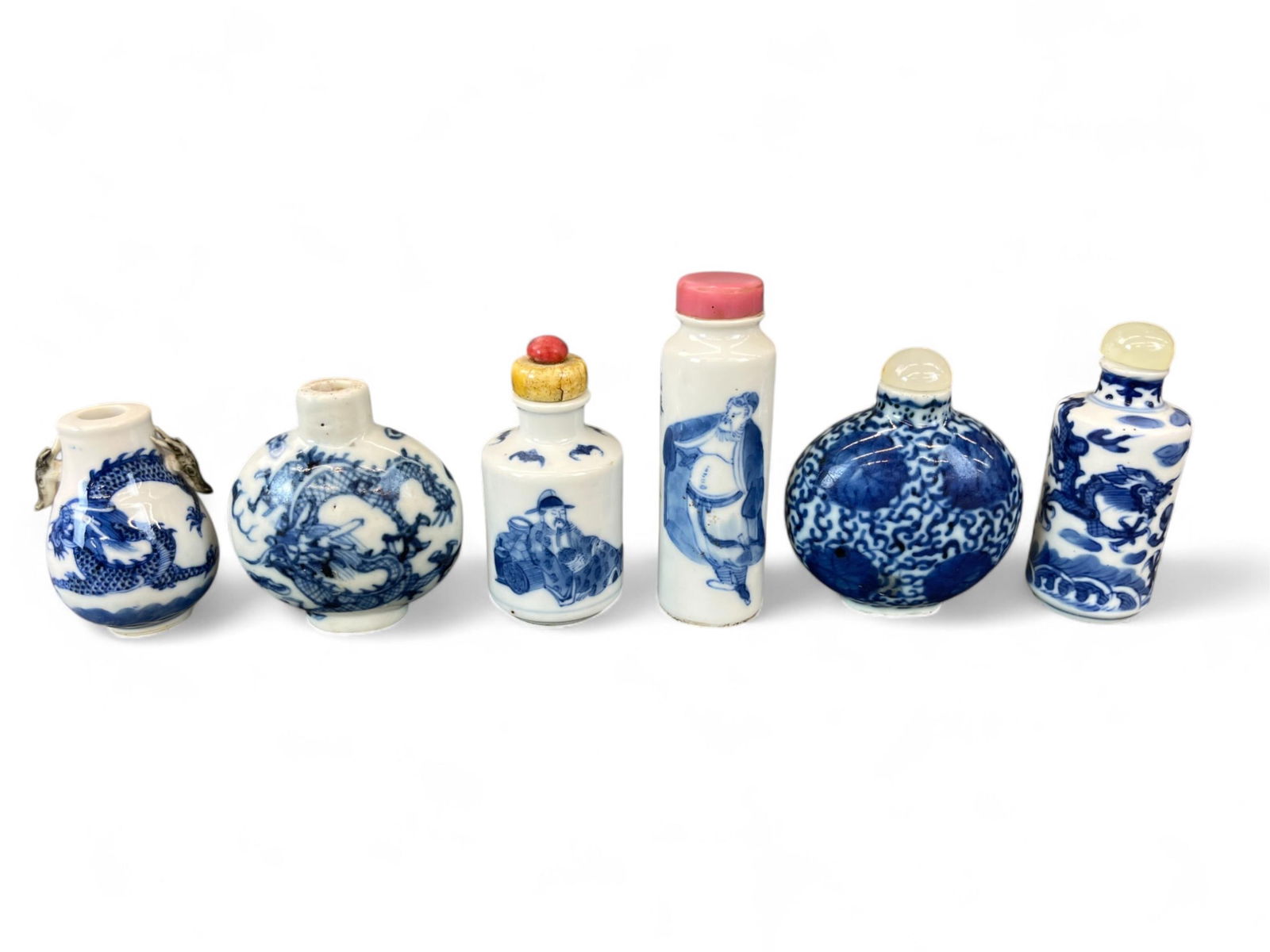 6 Blue and white porcelain snuff bottles.: A group of six blue and white porcelain snuff bottles. Two are marked on bottom. Smallest: 2 1/4" x 1 3/4". Largest: 3 1/2" x 1 1/8". Condition: Abrasions, residue, and two are missing stoppers. Prove
