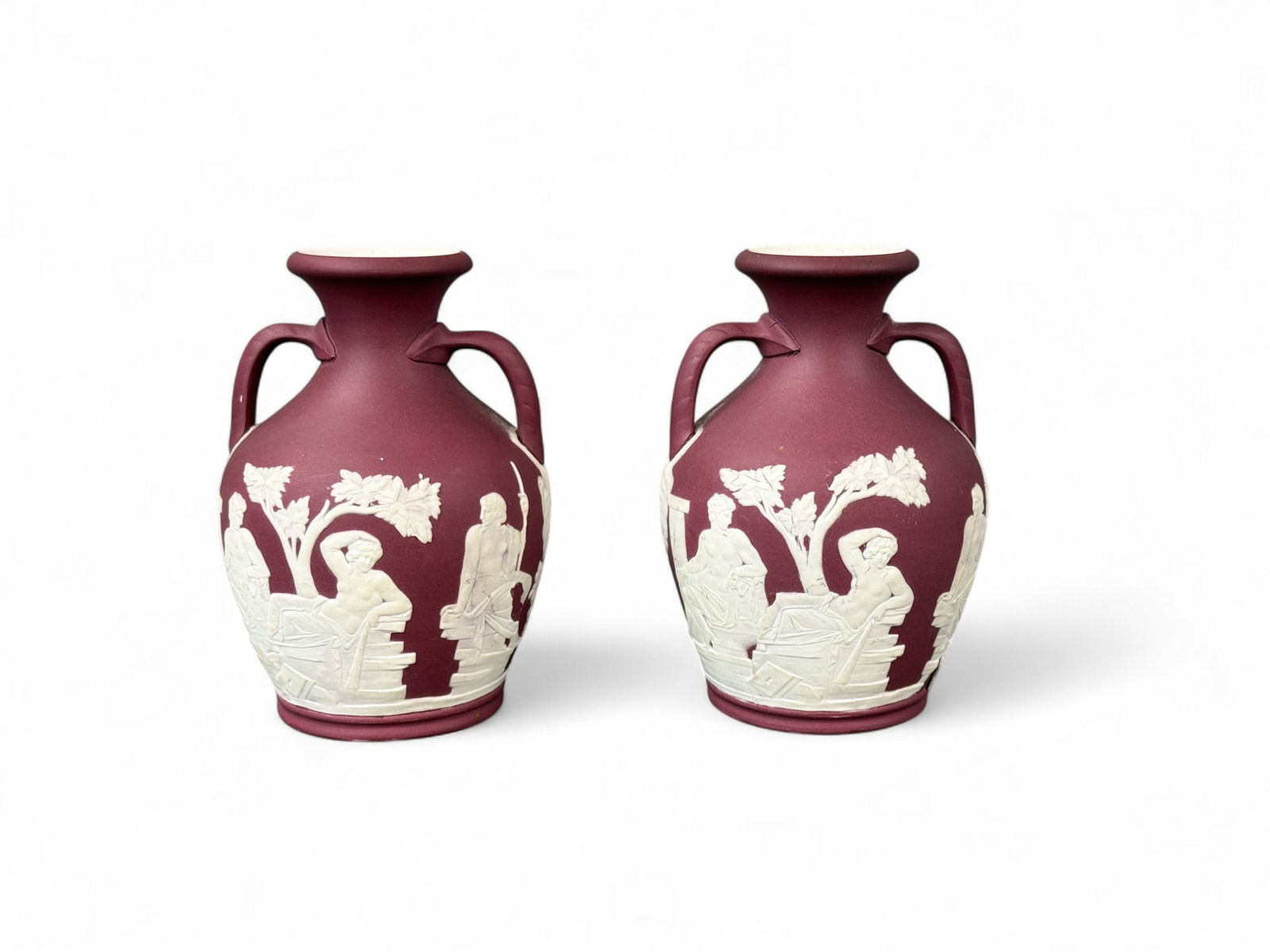 2 Wedgwood Jasperware Portland vases.: A pair of crimson Wedgwood Jasperware Portland vases. Early 20th century. 5" x 3 1/2". Condition: Surface dirt, residue, loss, and small cracks near handles. Provenance: Purchased from Bonhams in 2024
